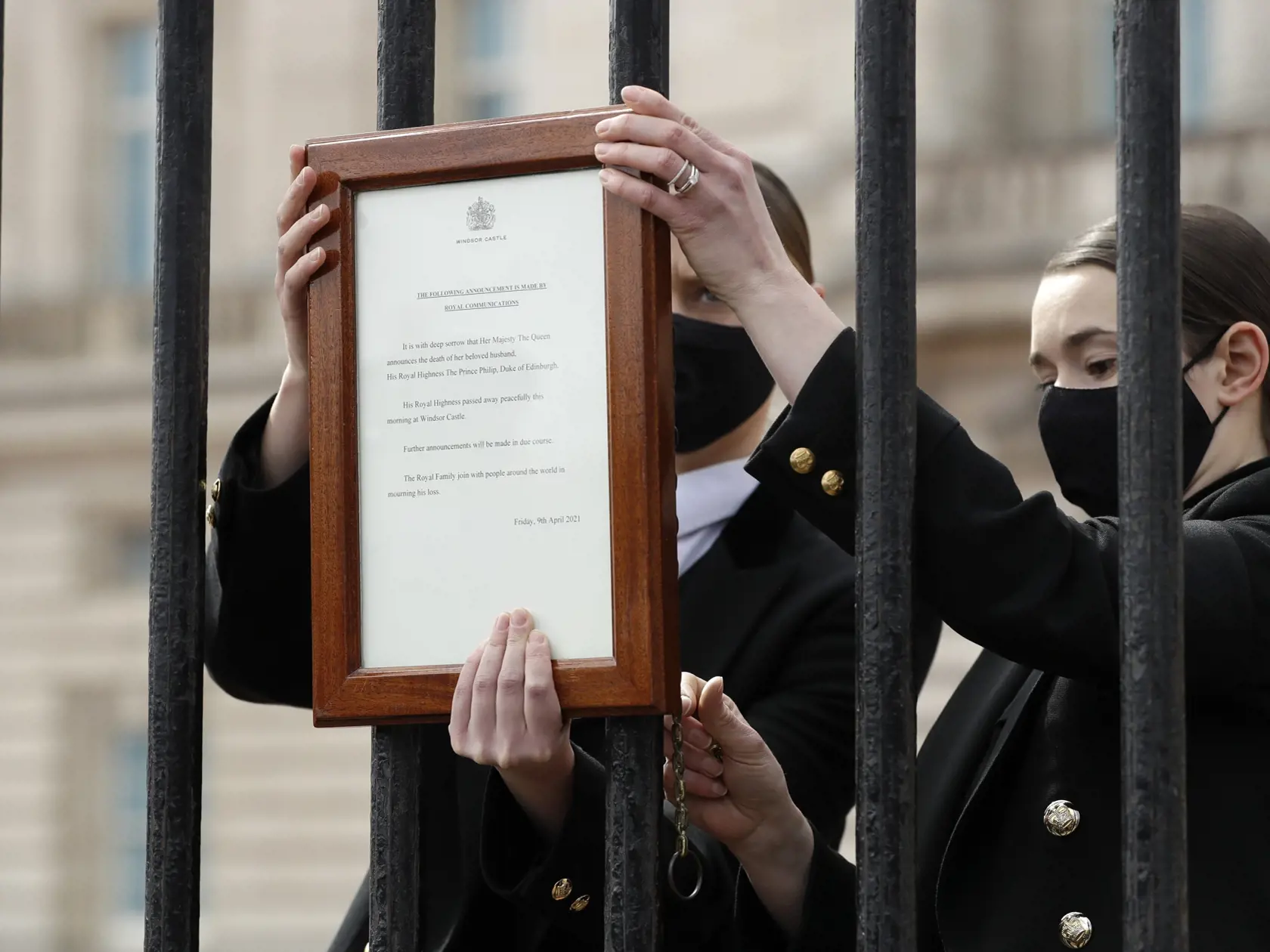 KK12 Londýn - Členovia personálu vešajú oznámenie o úmrtí britského princa Philipa na bránu Buckinghamského paláca 9. apríla 2021 v Londýne. Britský princ Philip, manžel kráľovnej Alžbety II., zomrel v piatok vo veku 99 rokov. Oznámil to Buckinghamský palác.  "Jeho kráľovská výsosť zomrela dnes ráno pokojne na Windsorskom zámku," dodal palác s tým, že ďalšie informácie zverejnia v náležitom čase. FOTO TASR/AP
Members of staff attach an announcement, regarding the death of Britain's Prince Philip
