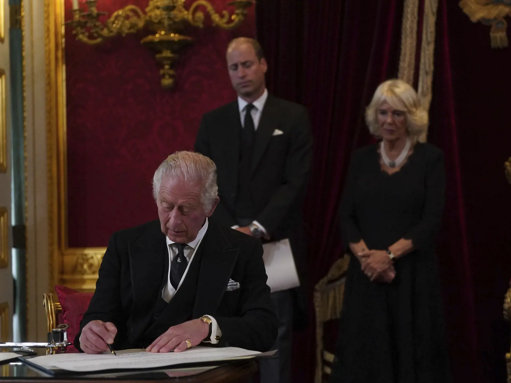 Na snímke v popredí britský kráľ Karol III. podpisuje prísahu počas zasadnutia rady pre nástupníctvo trónu v Paláci svätého Jakuba v Londýne 10. septembra 2022. Karol III. sa v sobotu predpoludním počas zasadnutia rady pre nástupníctvo trónu v Paláci svätého Jakuba stal novým britským kráľom. FOTO TASR/AP