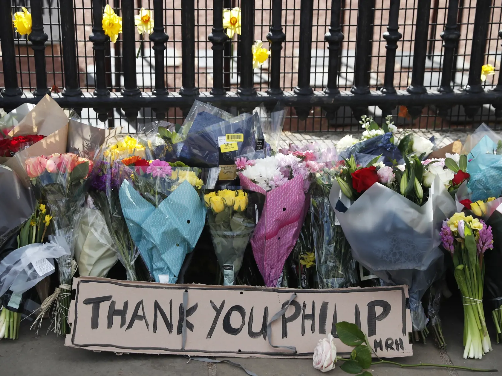 KK38 Londýn - Na snímke odkaz a kvety pred Buckinghamským palácom po oznámení o úmrtí britského princa Philipa 9. apríla 2021 v Londýne. Britský princ Philip, manžel kráľovnej Alžbety II., zomrel v piatok vo veku 99 rokov. Oznámil to Buckinghamský palác.  "Jeho kráľovská výsosť zomrela dnes ráno pokojne na Windsorskom zámku," dodal palác s tým, že ďalšie informácie zverejnia v náležitom čase. FOTO TASR/AP
A note and flowers are left at the front of the gate at Buckingham Palace in London, after 