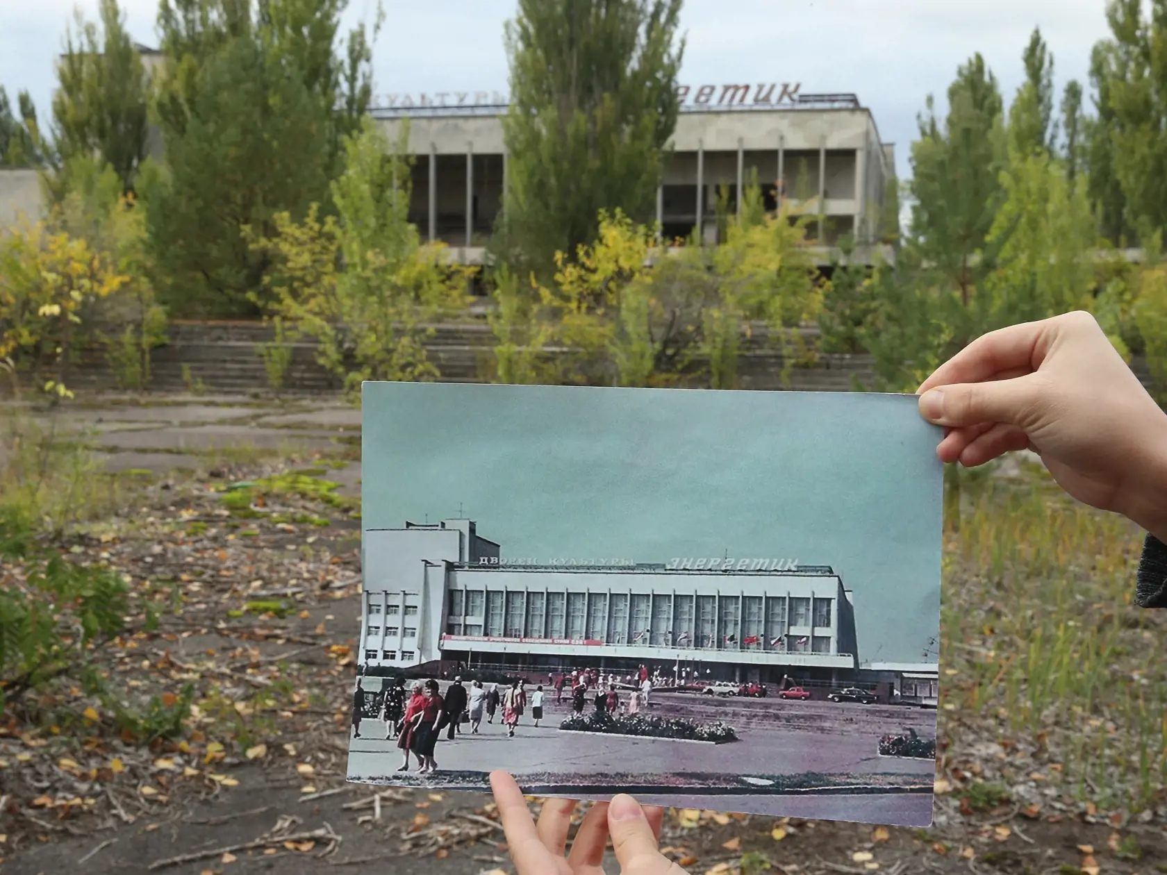 PRIPYAT, UKRAINE - SEPTEMBER 29:  An assistant holds up a photo showing the city of Pripyat's main square and the "Energetik" cultural center before 1986 at the same site that today is abandoned and overgrown with trees on September 29, 2015 in Pripyat, Ukraine. Pripyat lies only a few kilometers from the former Chernobyl nuclear power plant and was built in the 1970s to house the plant's workers and their families. On April 26, 1986, technicians at Chernobyl conducting a test inadvertently caus
