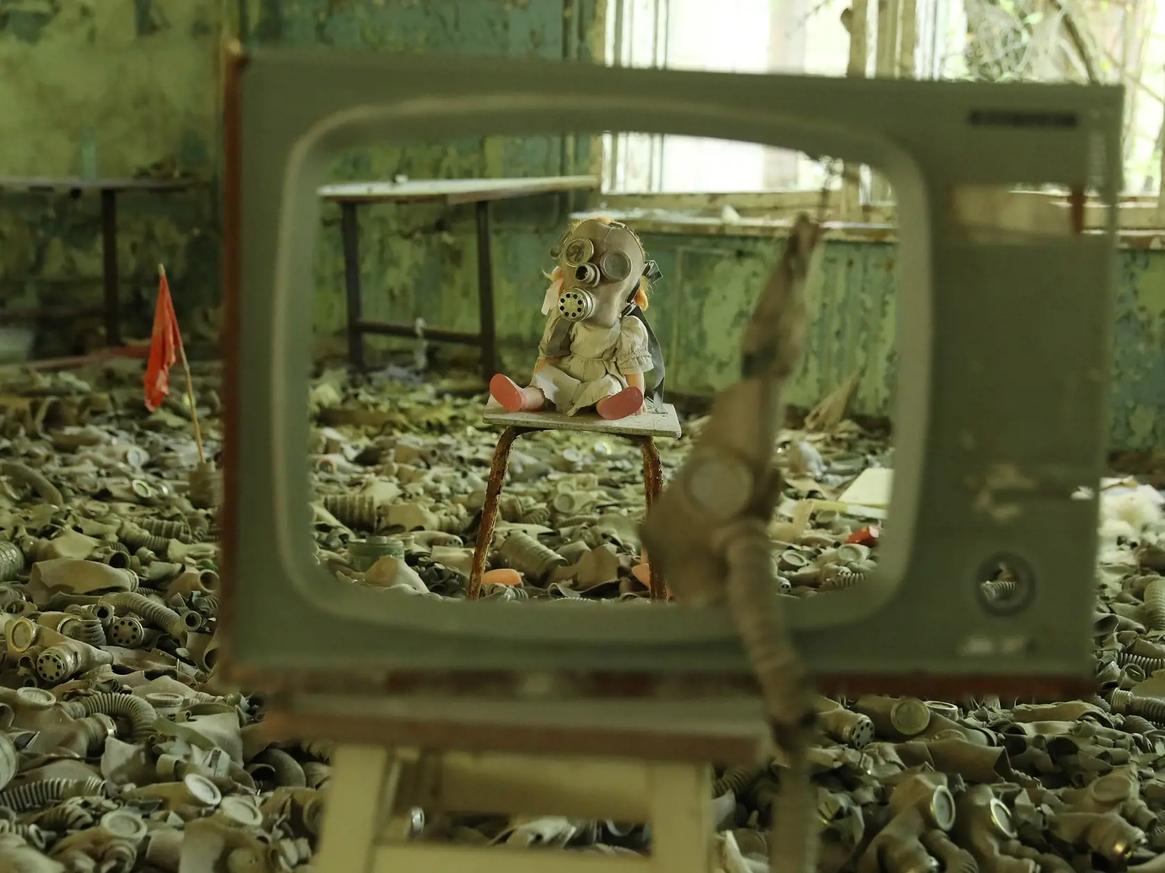PRIPYAT, UKRAINE - AUGUST 18:  A doll, likely arranged by a tourist, dressed with a gas mask sits on a chair among and old television and hundreds of gas masks lying on the floor of abandoned School Number 3 in the ghost town of Pripyat not far from the Chernobyl nuclear power plant on August 18, 2017 in Pripyat, Ukraine. On April 26, 1986 reactor number four exploded after a safety test went wrong, spreading radiation over thousands of square kilometers in different directions. The nearby town 