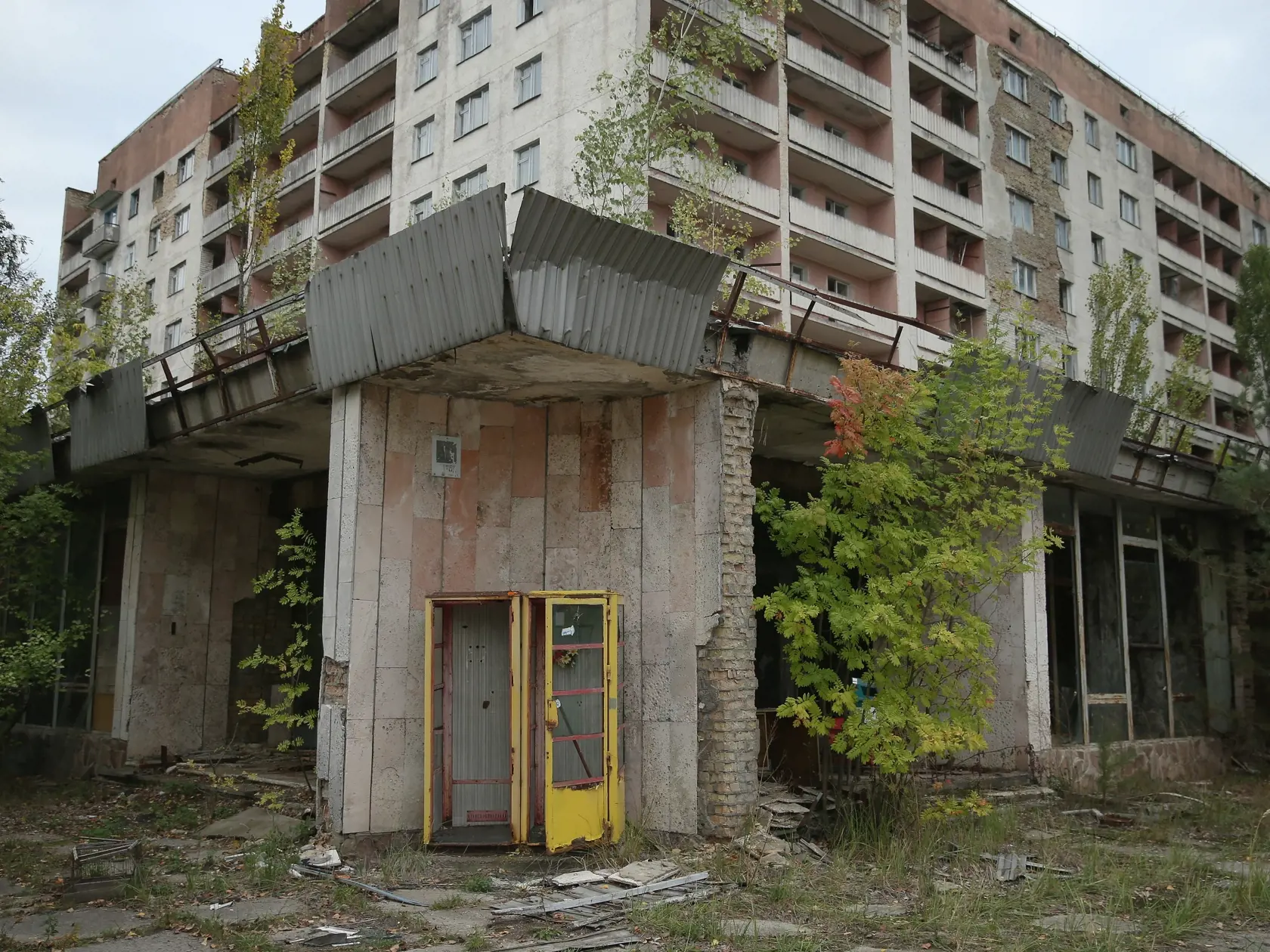 PRIPYAT, UKRAINE - SEPTEMBER 29:  A rusting phone booth stands outside an abandoned furniture store and apartment building on September 29, 2015 in Pripyat, Ukraine. Pripyat lies only a few kilometers from the former Chernobyl nuclear power plant and was built in the 1970s to house the plant's workers and their families. On April 26, 1986, technicians at Chernobyl conducting a test inadvertently caused reactor number four to explode, sending plumes of highly radioactive particles and debris into