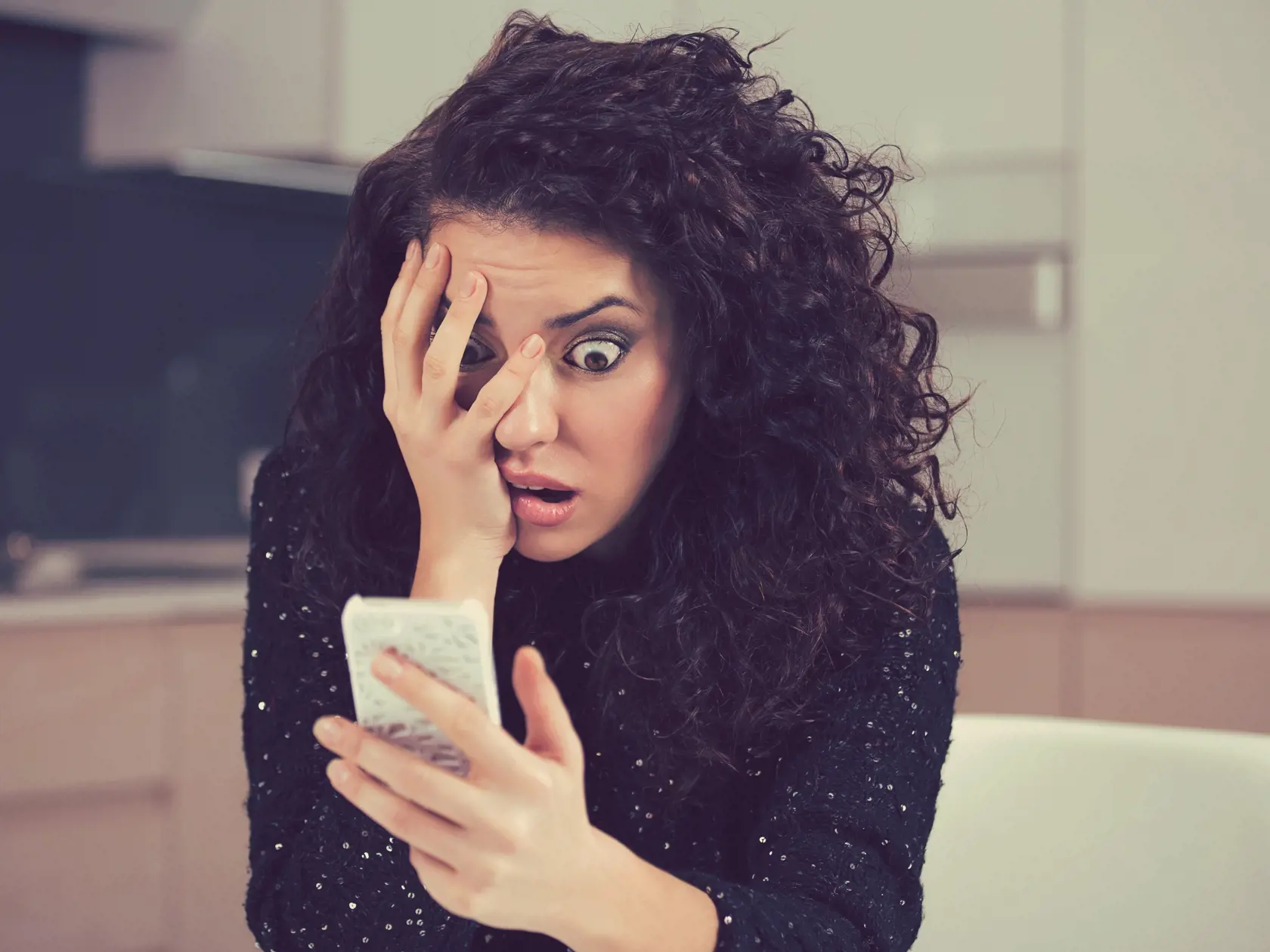 Young shocked anxious woman looking at phone seeing bad news photos message with scared emotion on face