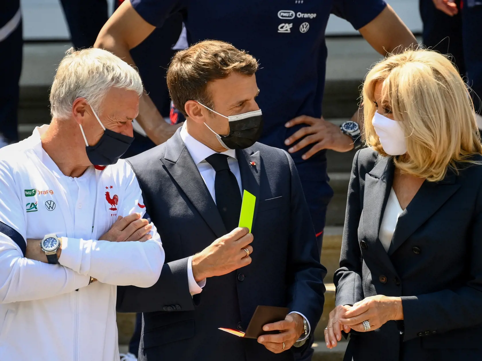 KK34 Clairefontaine - Francúzsky prezident Emmanuel Macron (uprostred) ukazuje žltú kartu, vpravo jeho manželka Brigitte Macronová a vľavo tréner francúzskej futbalovej reprezentácie Didier Deschamps v tréningovom kempe v Clairefontaine 10. júna 2021.