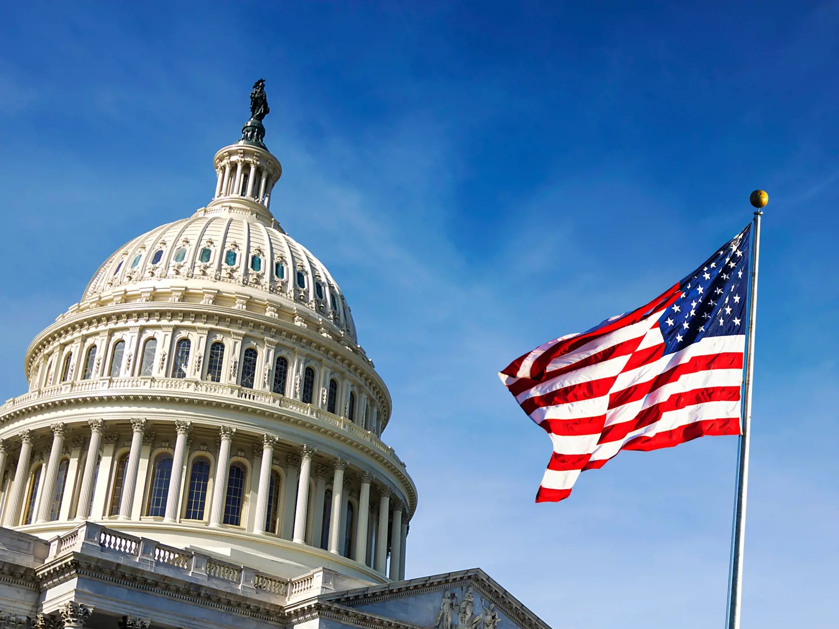 American,Flag,Waving,With,The,Capitol,Hill,In,The,Background