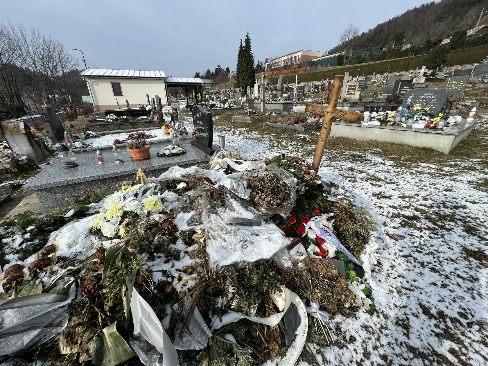 Namiesto pomníka tu dočasne stojí len jednoduchý drevený kríž a hrob pôsobí ako keby sa oň nik nestaral - ležia na ňom staré kvety ešte od pohrebu.