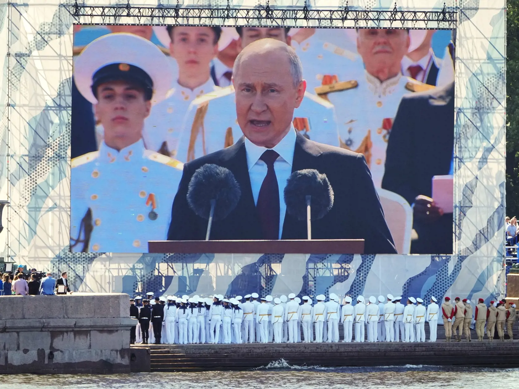 Príslušníci ruského námorníctva sledujú príhovor ruského prezidenta Vladimira Putina na obrovskej obrazovke pri príležitosti Dňa námorníctva v Petrohrade v nedeľu 30. júla 2023.