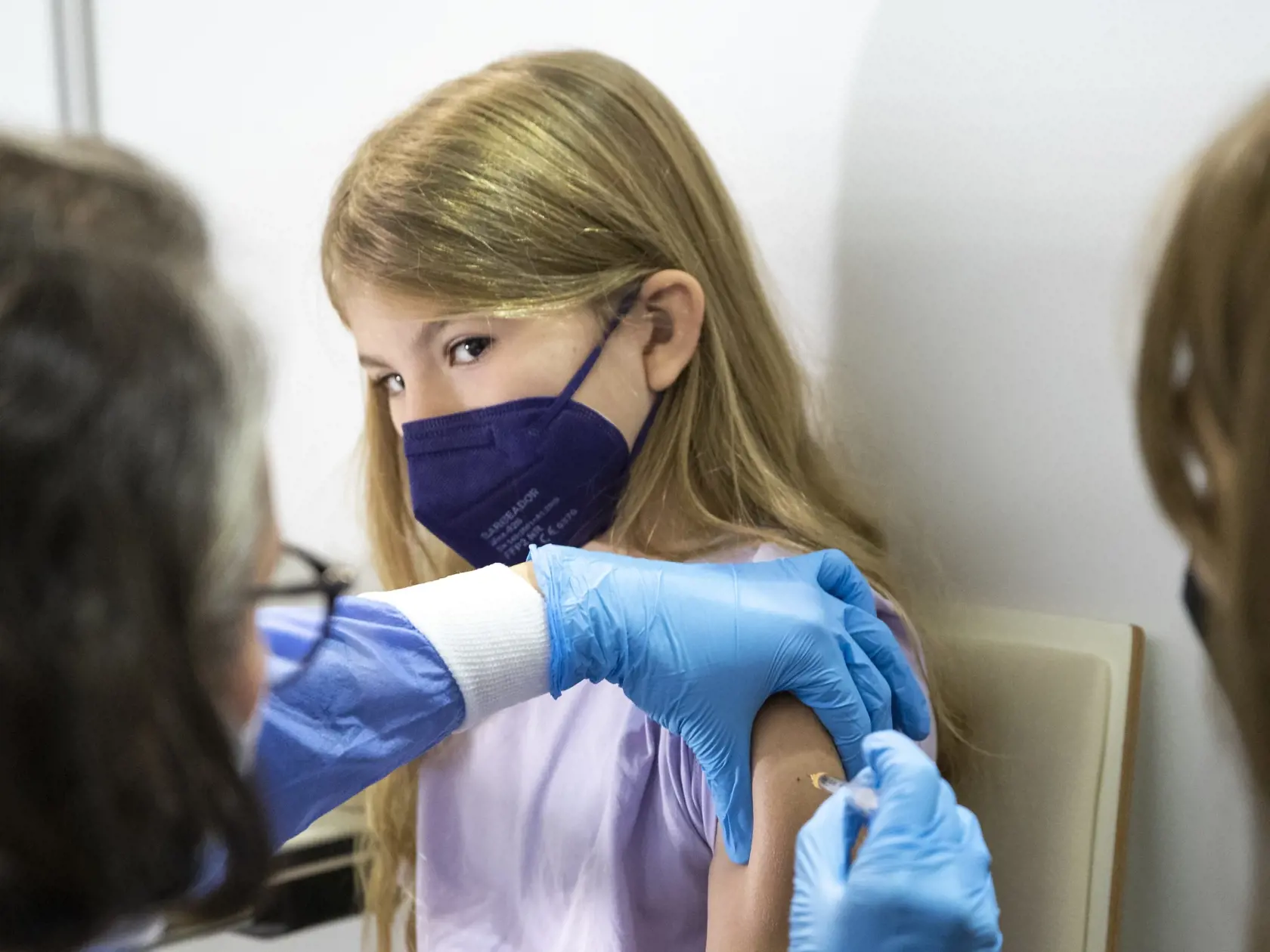 Dievča dostáva vakcínu Pfizer počas očkovania detí proti ochoreniu COVID-19.