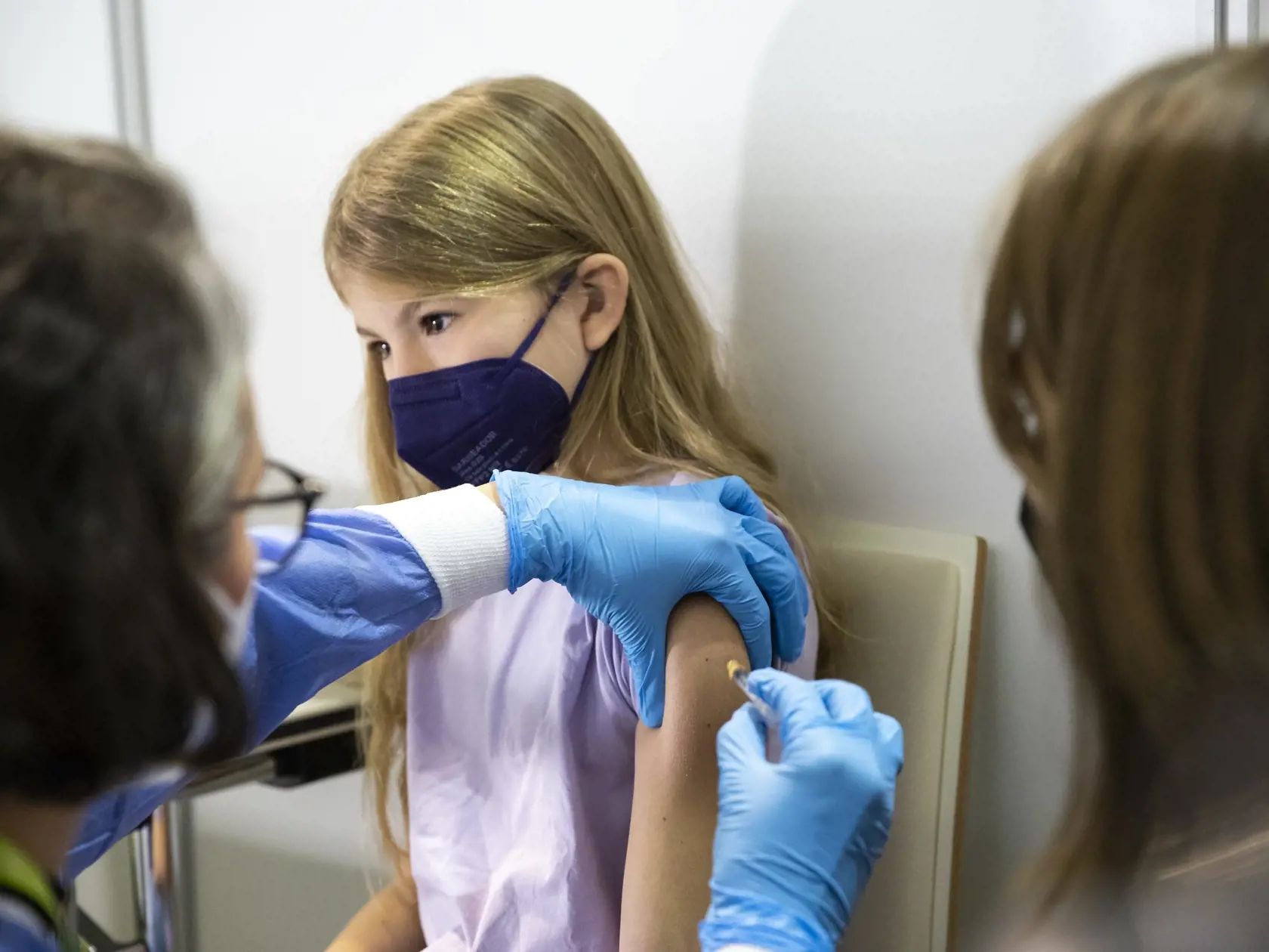 Dievča dostáva vakcínu Pfizer počas očkovania proti ochoreniu COVID-19 vo vakcinačnom centre.