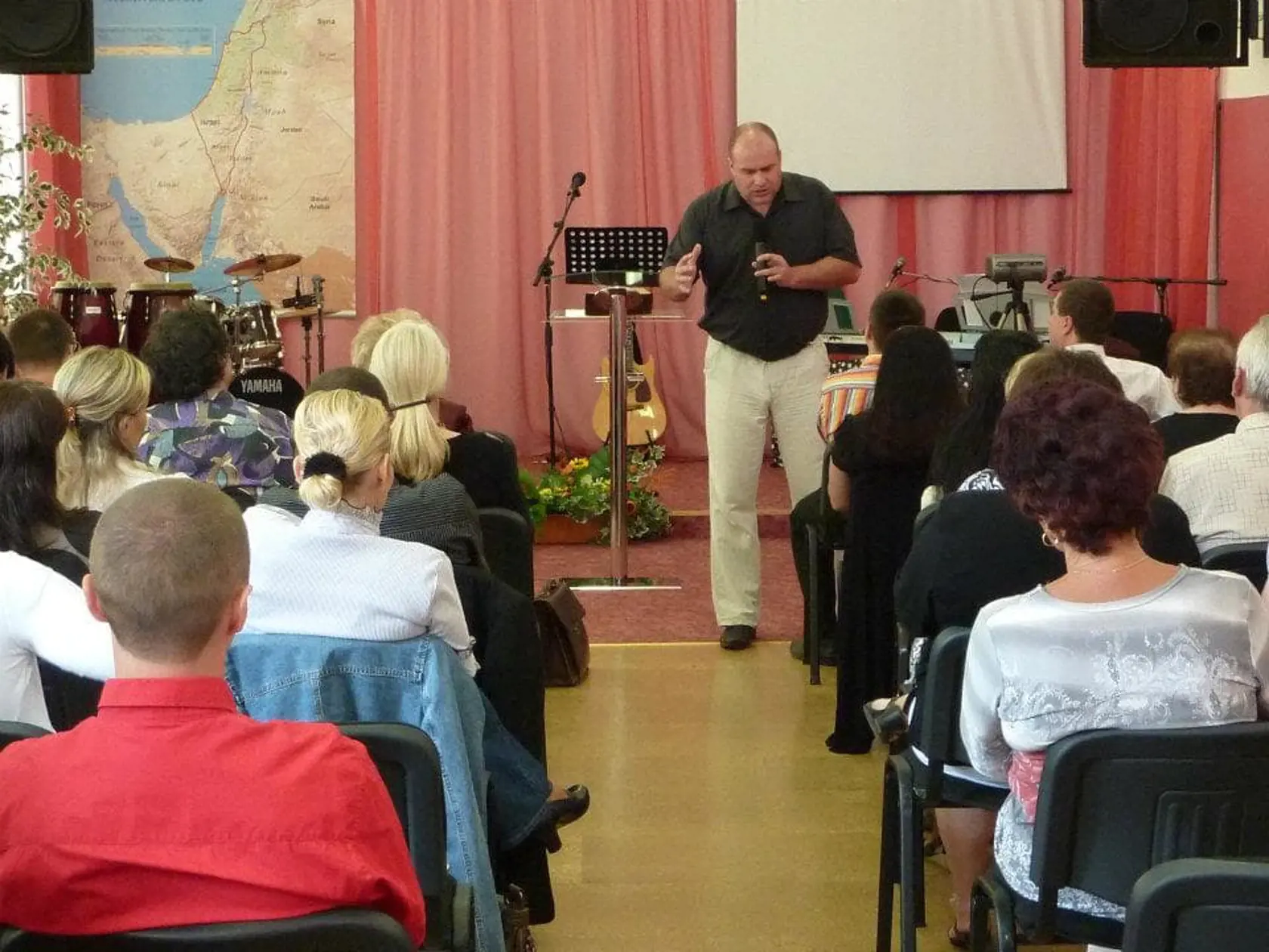 Ľudia v tichosti počúvajú kázeň od pastora.