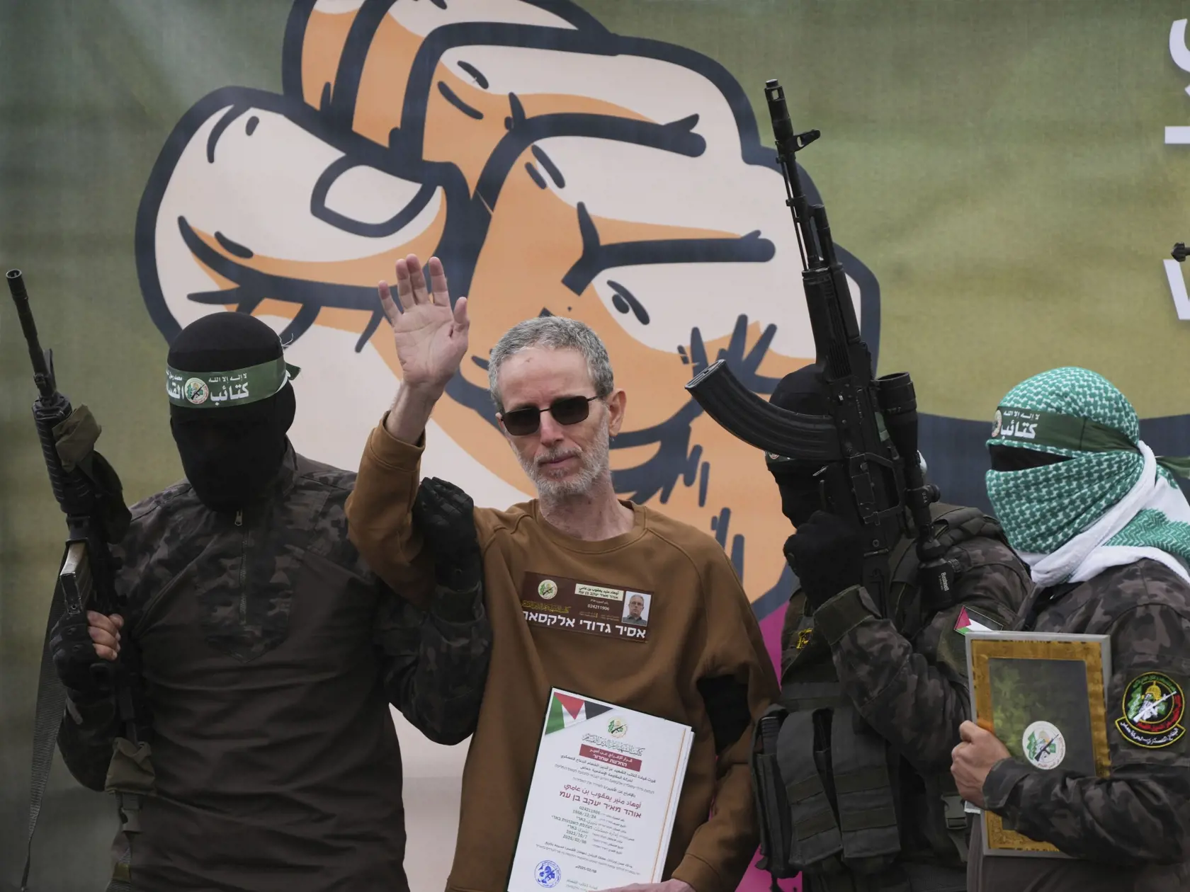 Unesený izraelský rukojemník Ohad Ben Ami, ktorý bol v zajatí od útoku palestínskeho militantného hnutia Hamas na juh Izraela zo 7. októbra 2023, pózujú s bojovníkmi Hamasu pred svojím odovzdaním Červenému krížu v meste Dajr al-Balah v Pásme Gazy v sobotu 8. februára 2025.