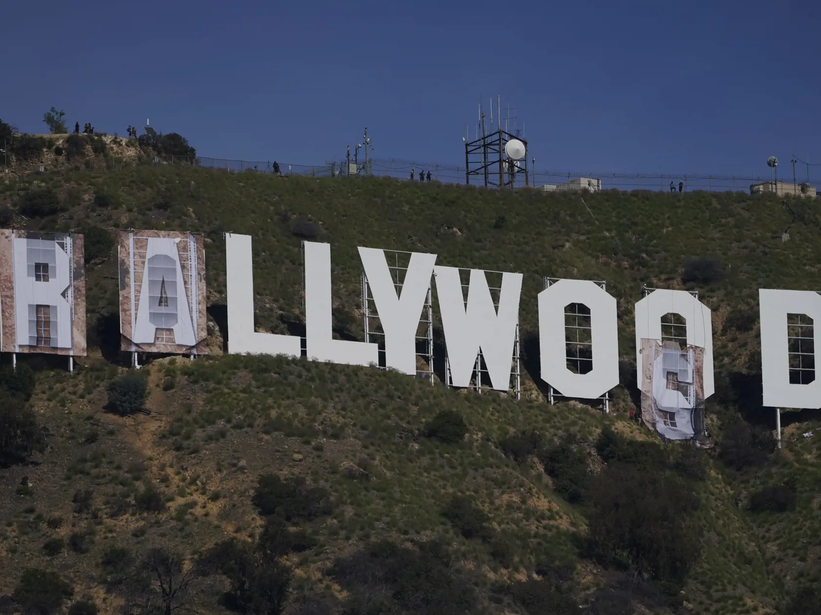 KK7 Los Angeles - Zamestnanci prekrývajú nápis Hollywood na "Rams House"  v Los Angeles 14. februára 2022. Ikonický nápis "Hollywood" nad americkým mestom Los Angeles zmenil na pár dní vizuálnu podobu. Na počesť víťazstva tamojšieho klubu Los Angeles Rams nad Cincinnati Bengals v nedeľnom Super Bowle zámorskej ligy amerického futbalu NFL ho v pondelok prekryli slovami "Rams House" (Domov Rams - pozn.). FOTO TASR/AP
Workers transform the Hollywood sign to read "Rams House" in Los Angeles on Monda