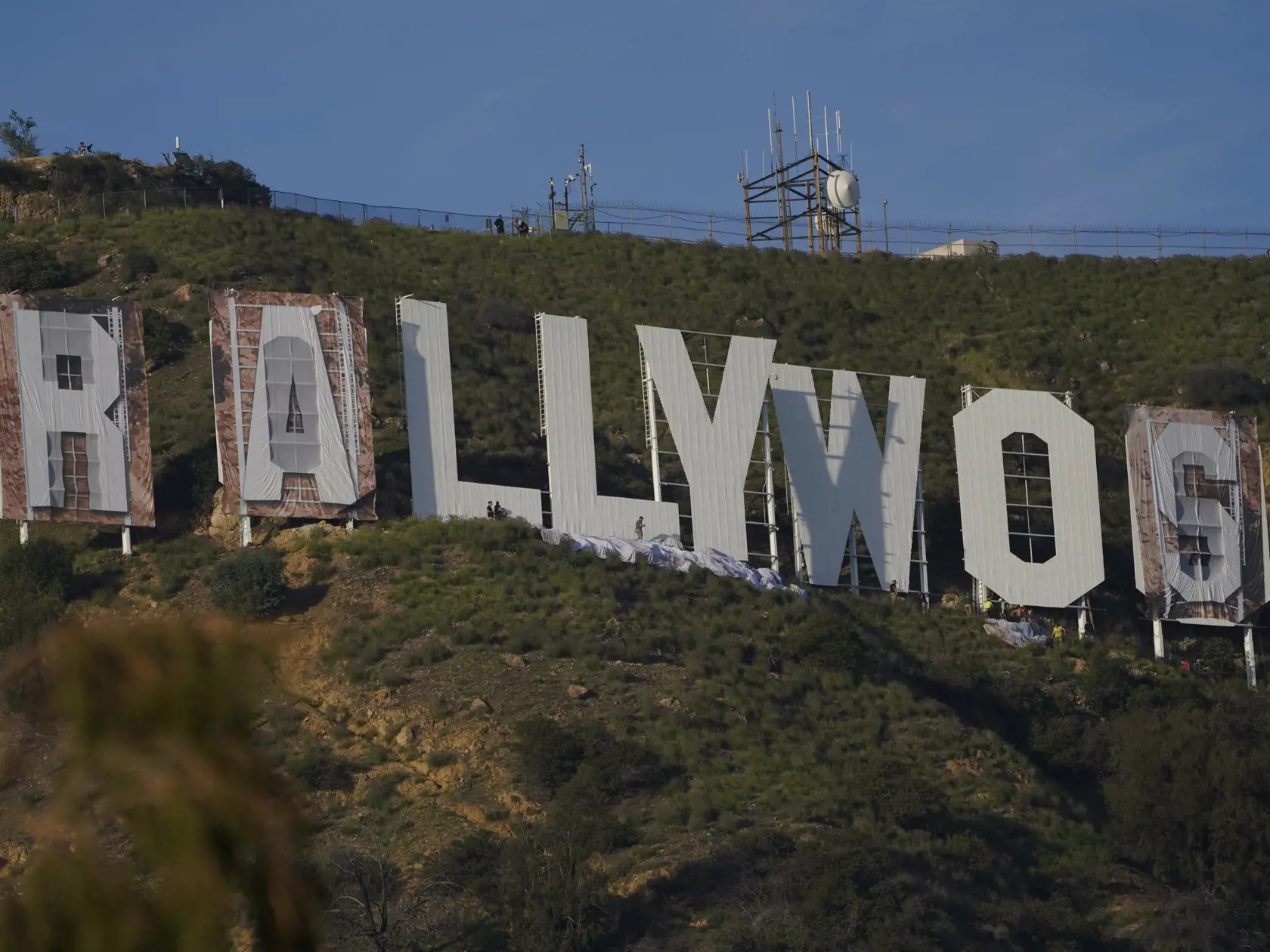 KK36 Los Angeles - Zamestnanci prekrývajú nápis Hollywood na "Rams House"  v Los Angeles 14. februára 2022. Ikonický nápis "Hollywood" nad americkým mestom Los Angeles zmenil na pár dní vizuálnu podobu. Na počesť víťazstva tamojšieho klubu Los Angeles Rams nad Cincinnati Bengals v nedeľnom Super Bowle zámorskej ligy amerického futbalu NFL ho v pondelok prekryli slovami "Rams House" (Domov Rams - pozn.). FOTO TASR/AP
Workers transform the Hollywood sign to read "Rams House" in Los Angeles on Mond