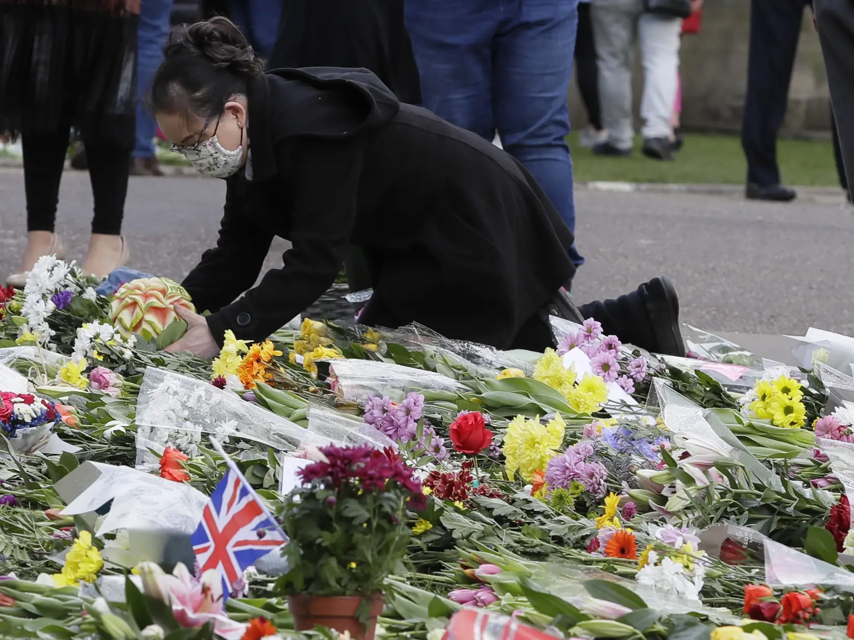 JB 26 Windsor - Žena kladie kvety pred Windsorským zámkom vo Windsore 12. apríla 2021. V Británii už prebiehajú prípravy poslednej rozlúčky s princom Philipom, manželom britskej kráľovnej Alžbety II., ktorý zomrel minulý piatok vo veku 99 rokov. Pohreb sa uskutoční v sobotu popoludní v areáli Windsorského zámku, informovala v pondelok stanica BBC. Pohrebné obrady sa budú konať v tamojšej kaplnke svätého Juraja o 15.00 h miestneho času (16.00 h SELČ). Celý obrad sa uskutoční výlučne v areáli zámk