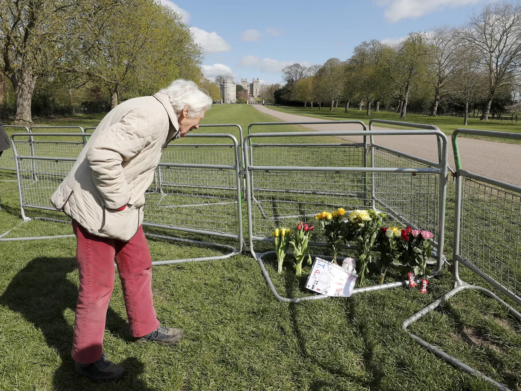 JB 1 Windsor - Žena sa pozerá na kvety položené na bariére pred Windsorským zámkom vo Windsore 15. apríla 2021. V Británii už prebiehajú prípravy poslednej rozlúčky s princom Philipom, manželom britskej kráľovnej Alžbety II., ktorý zomrel minulý piatok vo veku 99 rokov. Pohreb sa uskutoční v sobotu popoludní v areáli Windsorského zámku, informovala v pondelok stanica BBC. Pohrebné obrady sa budú konať v tamojšej kaplnke svätého Juraja o 15.00 h miestneho času (16.00 h SELČ). Celý obrad sa uskuto