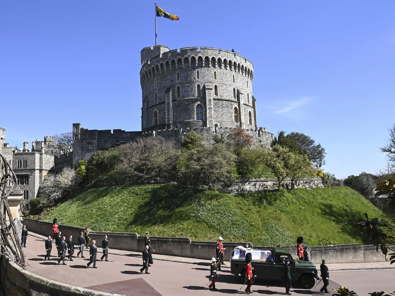 JB 84 Windsor - Členovia kráľovskej rodiny zľava britský princ Charles, princezná Anne, princ Andrew. princ Edward, princ William, Peter Phillips, princ Harry a Tim Laurence sprevádzajú rakvu pri prechádzaní okolo veže Round Tower počas pohrebu britského princa Philipa, manžela britskej kráľovnej Alžbety II., ktorý zomrel minulý piatok vo veku 99 rokov, v areáli Windsorského zámku vo Windsore 17. apríla 2021. Philipovo telo previezli zo súkromnej kaplnky pred vchod hradného areálu na špeciálne u