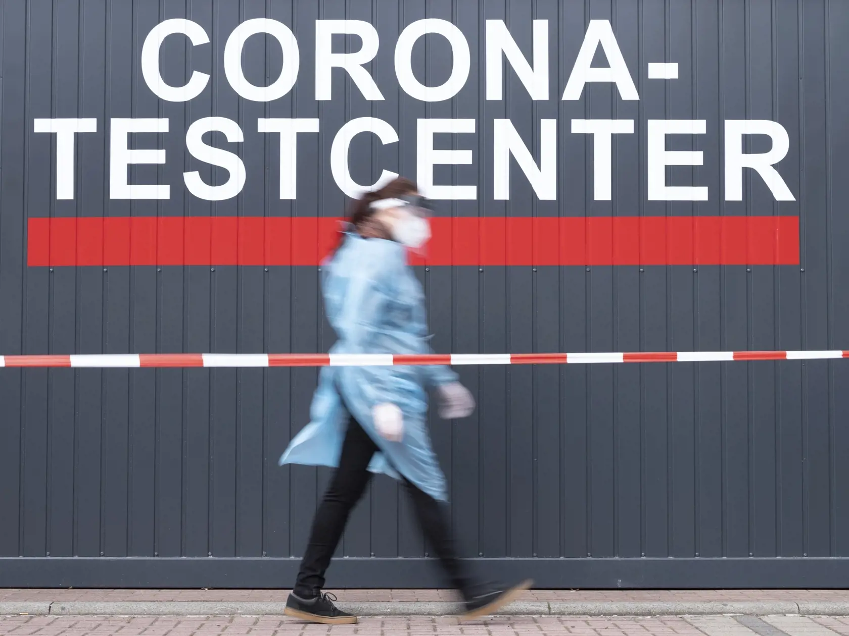 JB 38 Drážďany - Zdravotníčka prechádza okolo testovacieho centra na ochorenie COVID-19 v Drážďanoch 23. apríla 2021. Sporný nemecký zákon o ochrane pred infekciami, ktorý na celoštátnej úrovni zavádza tzv. ručnú brzdu pri vysokej incidencii nákazy a zjednocuje tak pravidlá v boji s koronavírusovou pandémiou pre všetkých 16 spolkových krajín Nemecka, vstúpi do platnosti v sobotu 24. apríla. Stane sa tak po tom, ako ho vo štvrtok schválila Spolková rada, podpísal ho prezident Frank-Walter Steinme