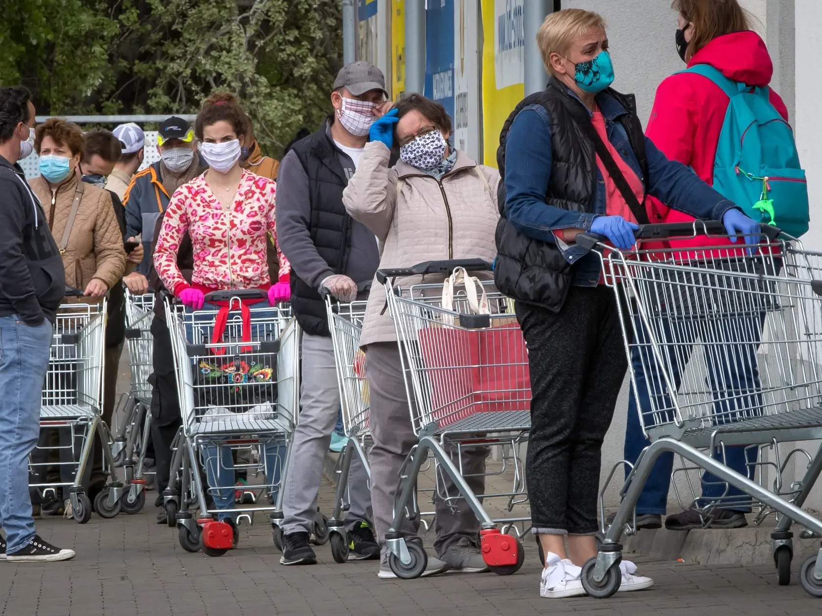 Nakupovanie potravín počas pandémie. Bezpečnostné opatrenia k zachovaniu odstupu zákazníkov počas nákupu. Na snímke sú ľudia, čakajúci na vstup do predajne.