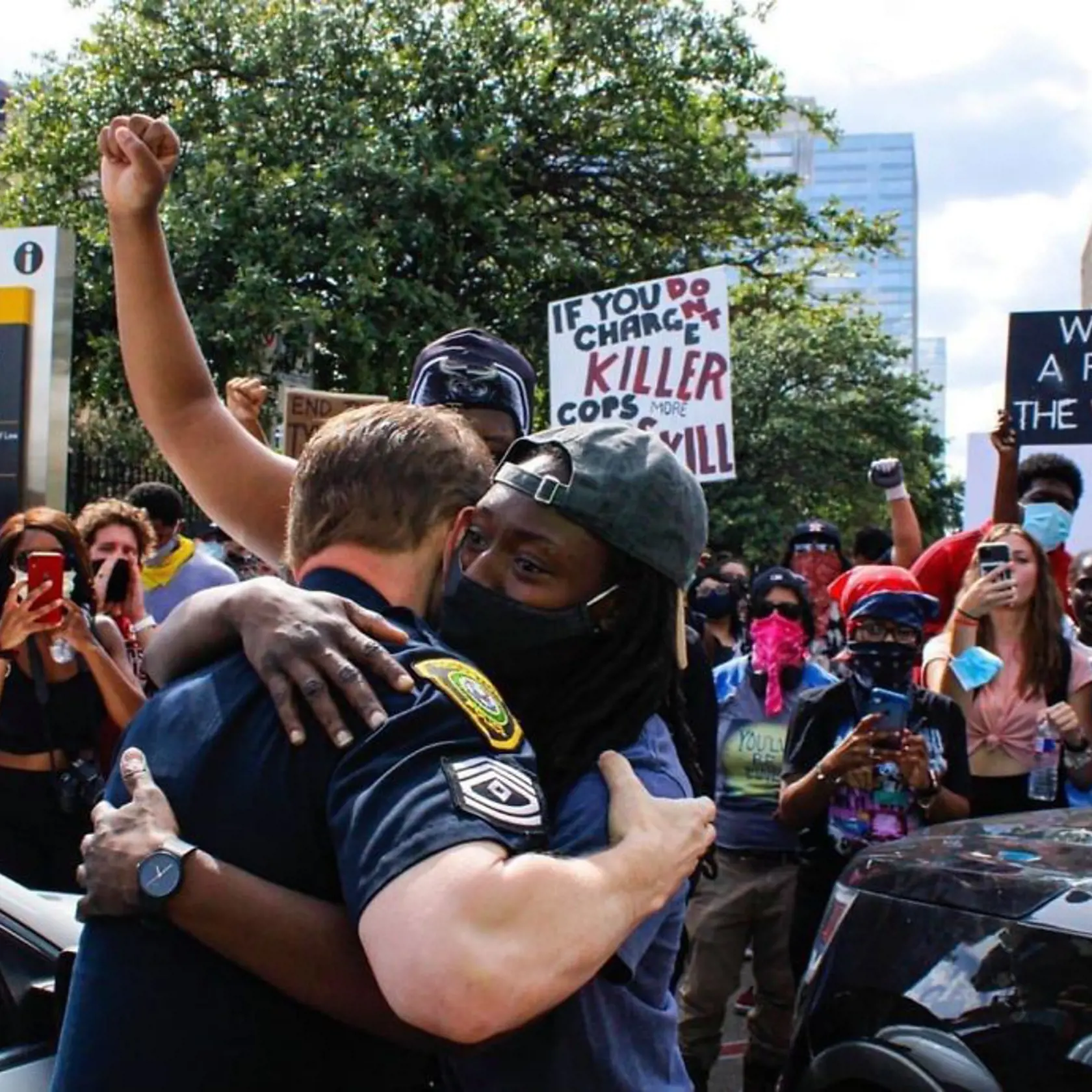 Policajt sa objíma s Afroameričanom počas násilných protestov.