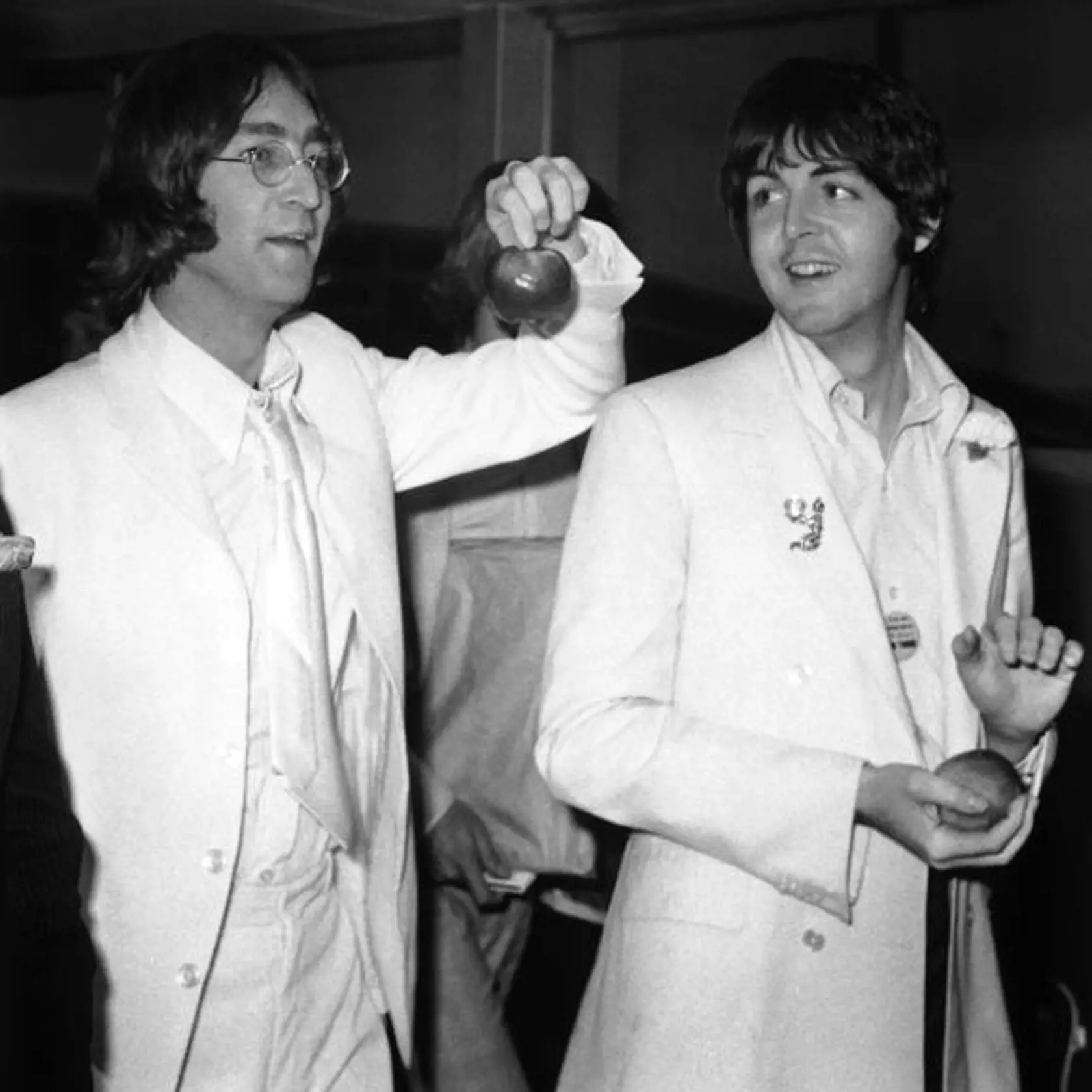 Beatles John Lennon and Paul McCartney at London Airport after a trip to America to promote their new company Apple Corps, 16th May 1968. They are both dressed all in white and carrying apples. (Photo by Stroud/Express/Getty Images)