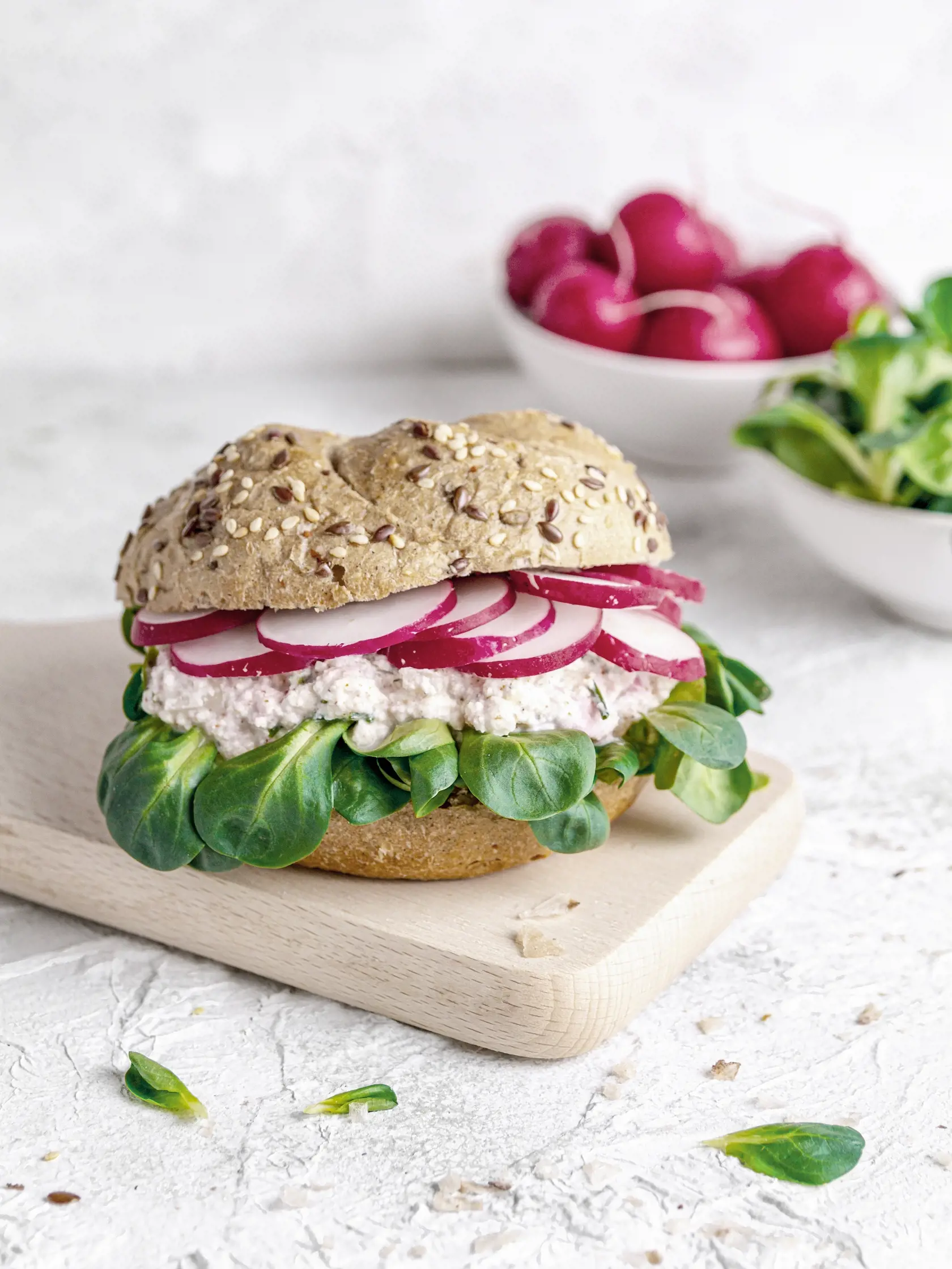 Spring sandwich with cottage cheese, radish, chives and lamb's lettuce on a light background