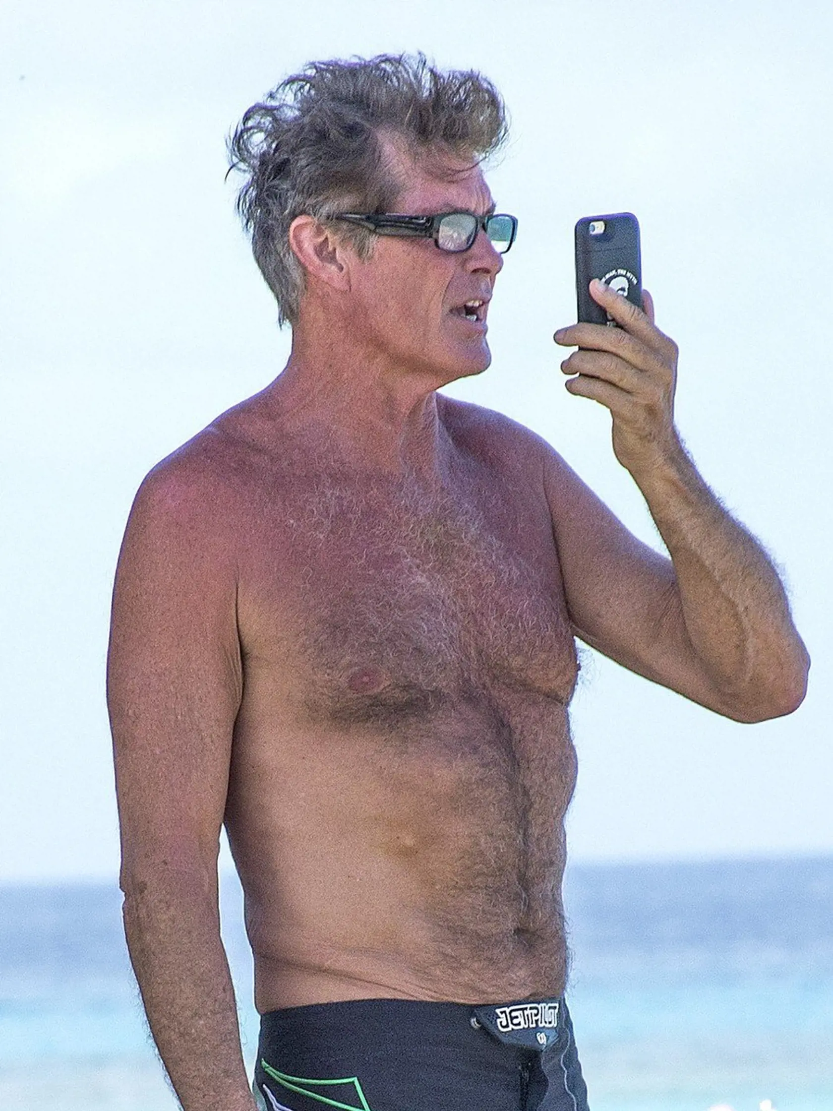 Picture Shows: David Hasselhoff  May 10, 2016    American actor David Hasselhoff is spotted taking selfies while relaxing on the beach on holiday in Barbados.    The 'Baywatch' star showed off his beach body, still impressive at the age of sixty-three, in a pair of black board shorts. The Hoff's phone case had the slogan 'The Man, The Myth - The ... '     Exclusive  WORLDWIDE RIGHTS, Image: 285194264, License: Rights-managed, Restrictions: Exclusive No Digital Rights Without Permission Please Cr