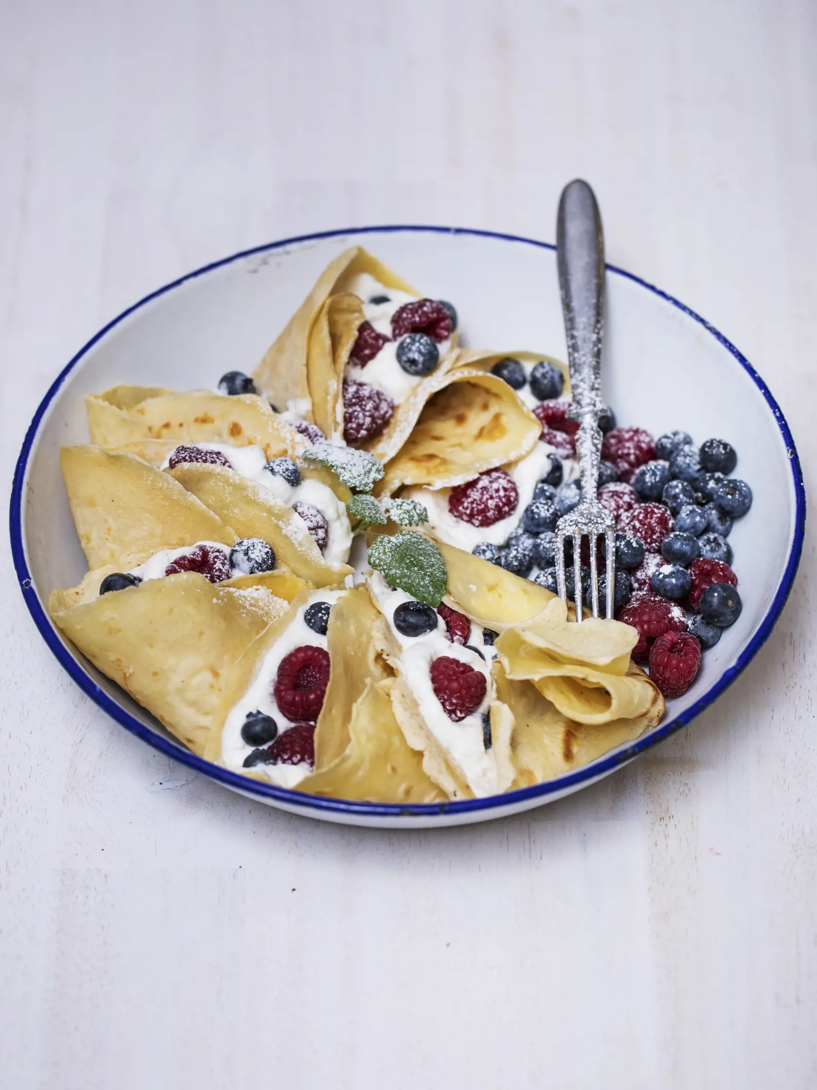 Palacinky naplňte medovou šľahačkou a pridajte maliny a čučoriedky.