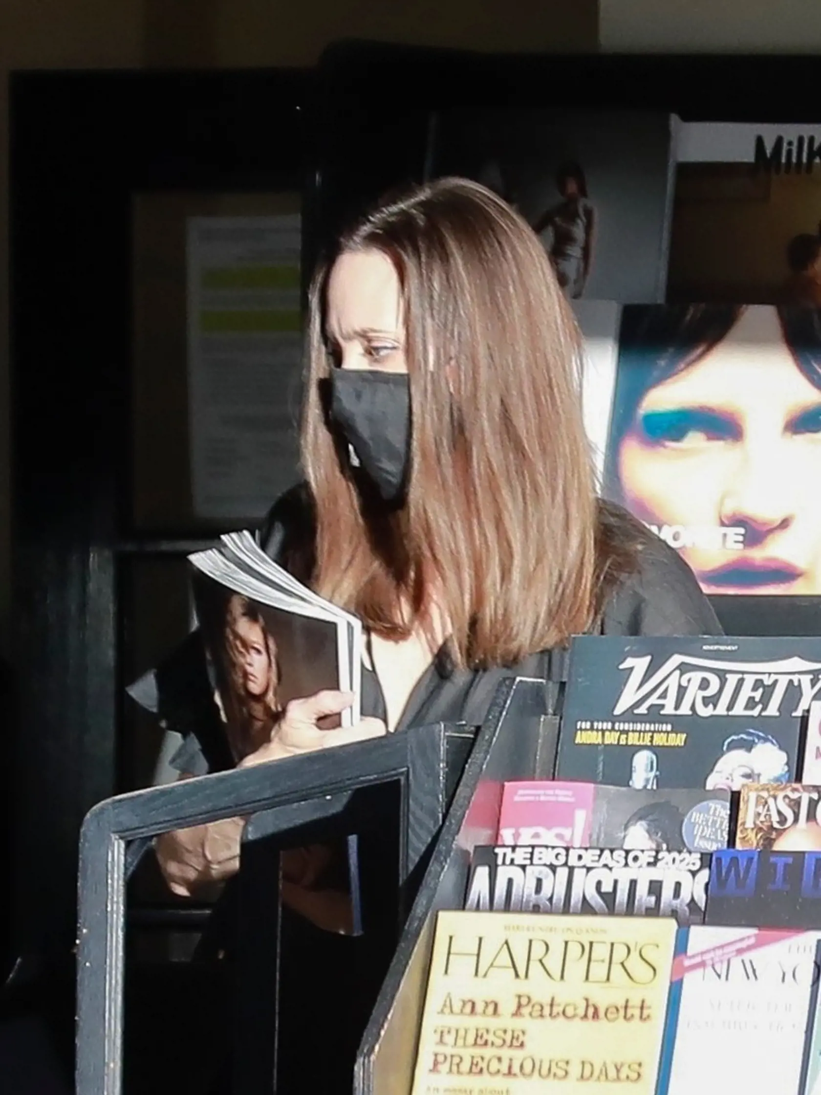 Angelina Jolie si vyberá časopisy.