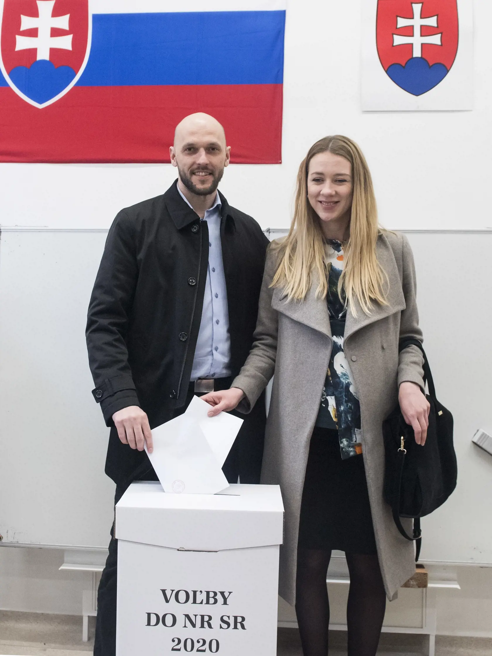 Michal Truban s partnerkou vhadzujú hlasovacie lístky v obálkach do volebnej schránky vo voľbách do Národnej rady SR vo volebnej miestnosti v Bratislave 29. februára 2020. FOTO TASR - Martin Baumann