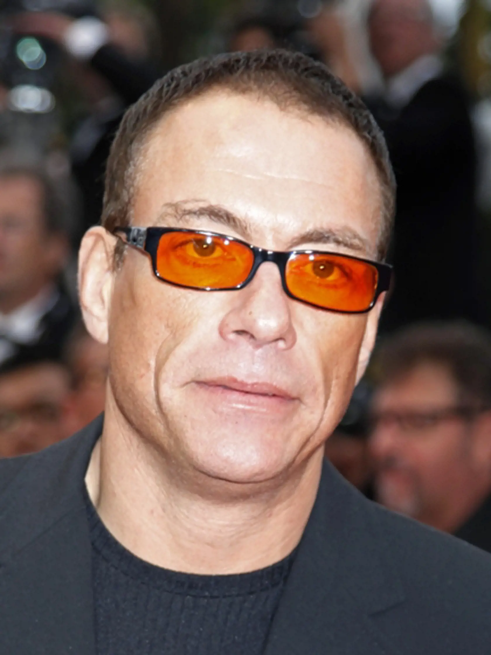 Jean-Claude van Damme. Okuliare s červenými sklami sú jeho poznávacím znamením.