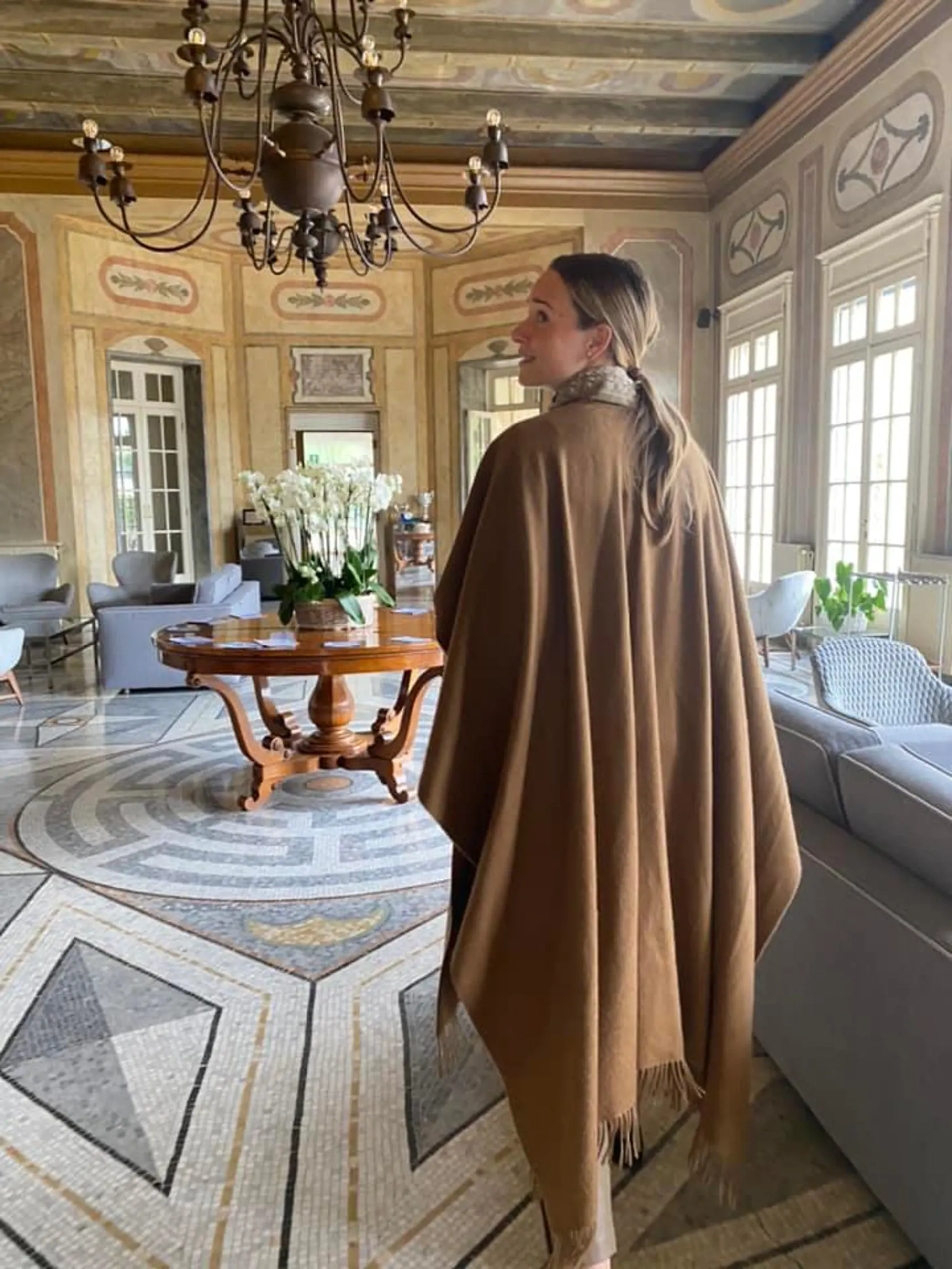 Na umeleckom zábere z krásneho interiéru v talianskom štýle a elegantným nábytkom sa nachádza poslankyňa Tabák odfotená v dlhom pončo so strapcami. Odev bývalej tenistky je hnedej farby a tak skvelo ladí s jemnými tónmi neutrálnych odtieňov zemitej a sivej farby vstupnej miestnosti.