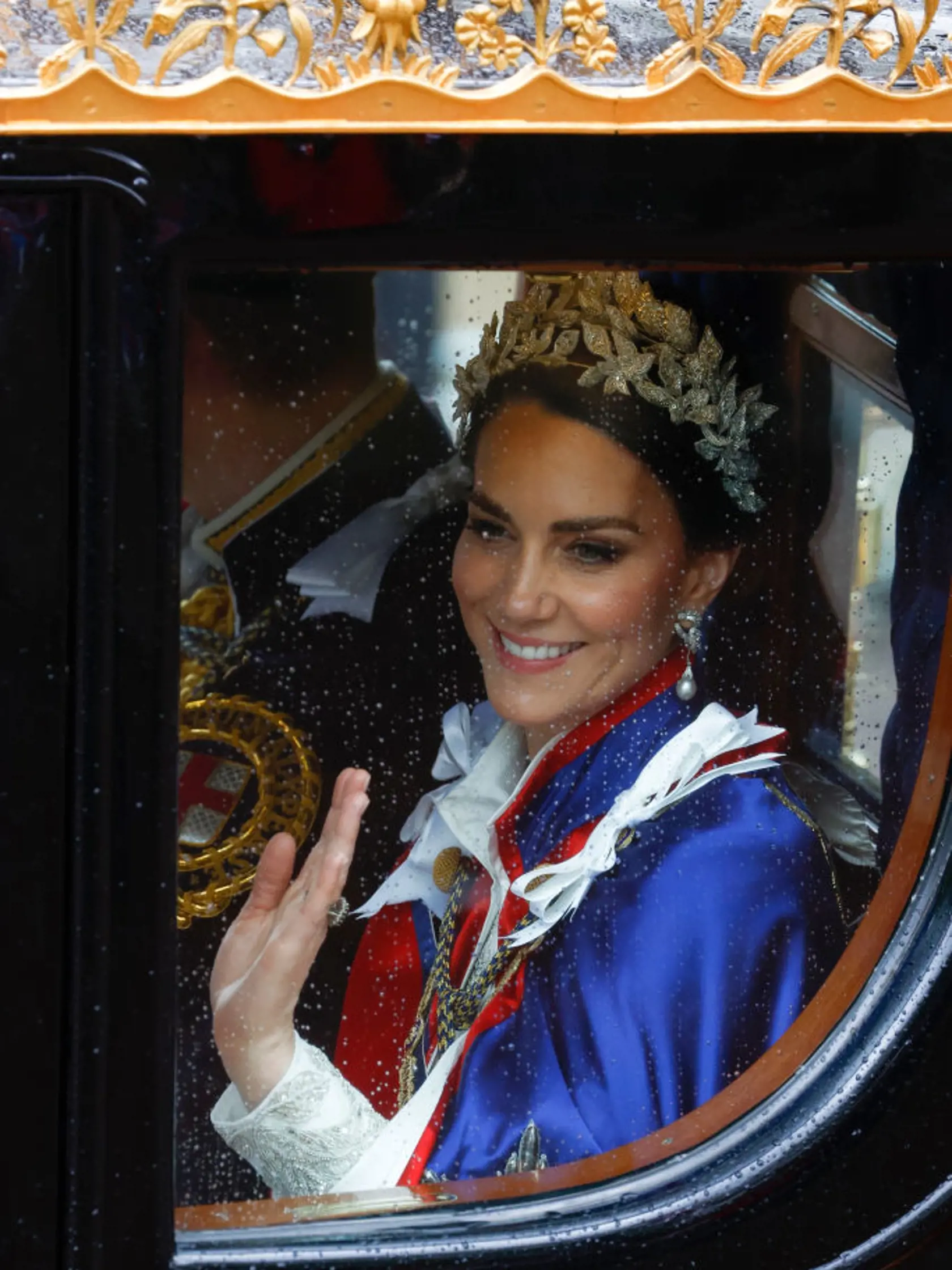 Princezná Kate mala na sebe tradičný ceremoniálny plášť. Pod ním slonovinové šaty od Alexandra McQueena a 3D čelenku, rovnako tak aj jej dcéra, princezná Charlotte.