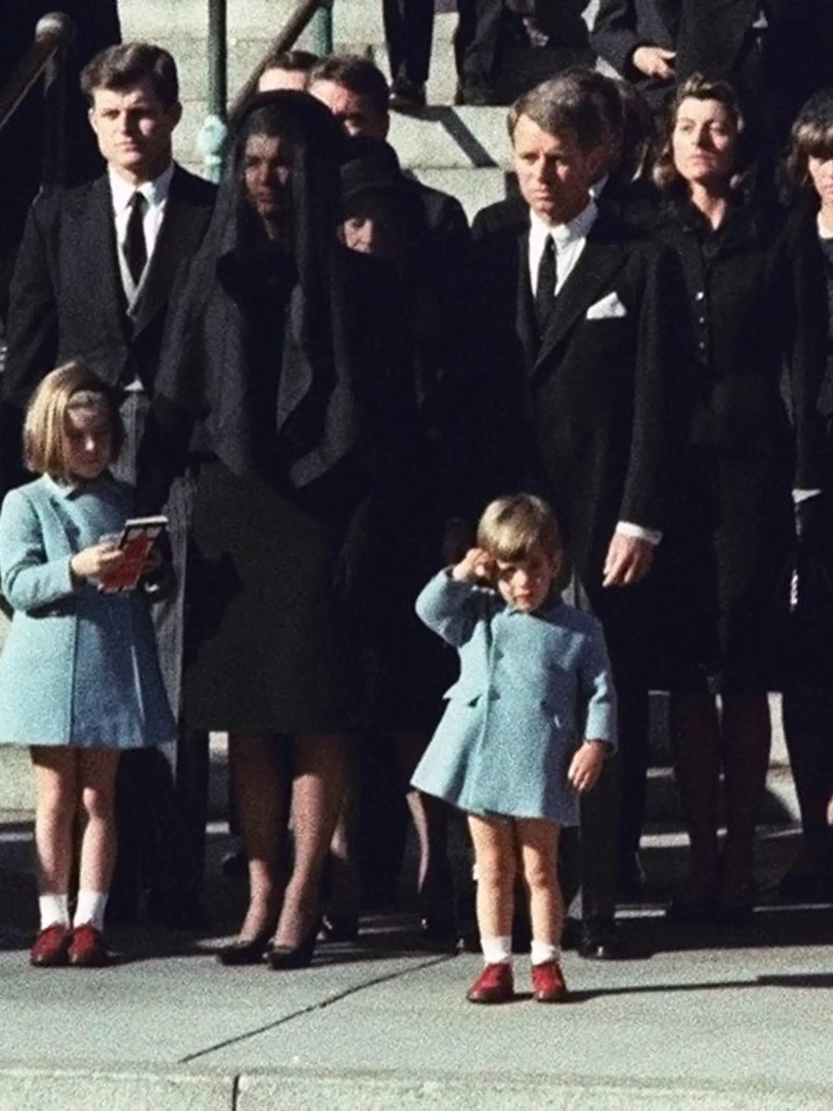 KK23 Washington - Na archívnej snímke z 25. novembra 1963 trojročný John F. Kennedy mladší salutuje pred truhlou svojho zavraždeného otca Johna F. Kennedyho. Vdova Jacqueline Kennedyová (uprostred) a dcéra Caroline Kennedyová stoja s bratmi jej zavraždeného manžela, Edwardom Kennedym (vľavo) a Robertom Kennedym. Dňa 22. novembra 2013 uplynie od atentátu na prezidenta Johna Fitzgeralda Kennedyho 50 rokov. Stalo sa to 22. novembra 1963 počas jeho cesty po Texase, ktorú absolvoval v súvislosti s bl