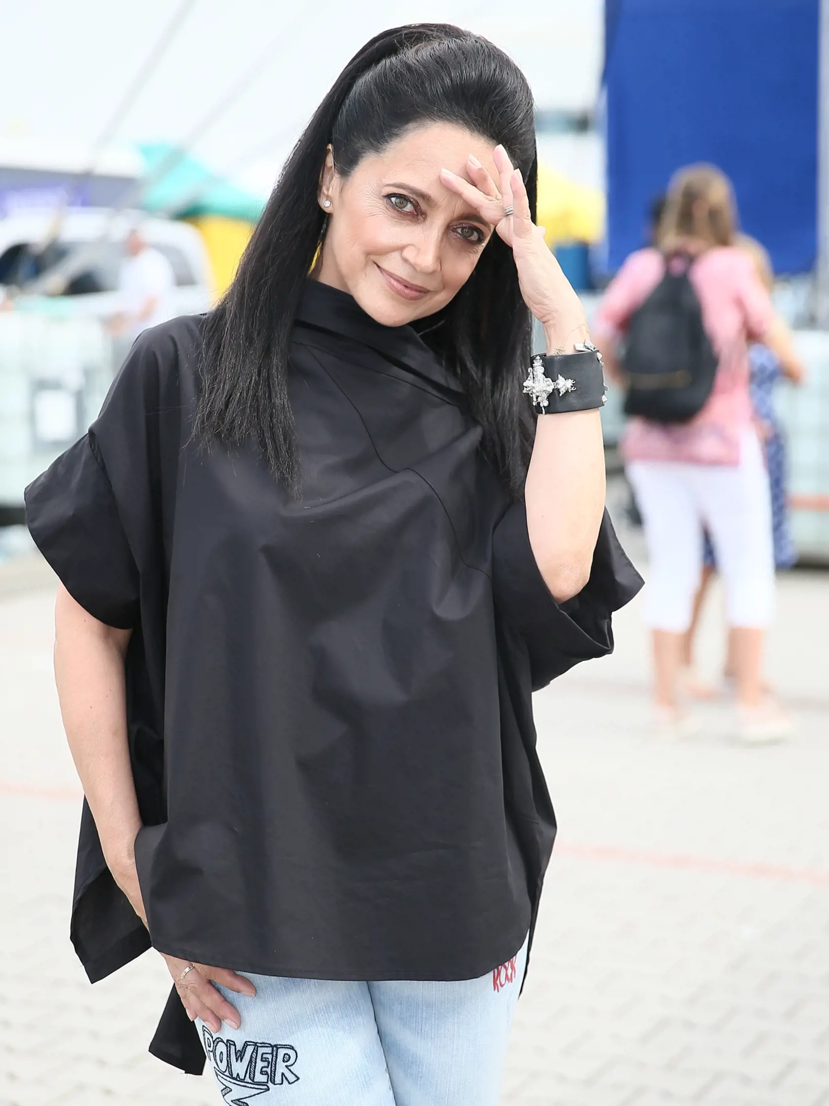 Lucie Bílá  skombinovala čiernu voľnú blúzku s popísanými rifľami.