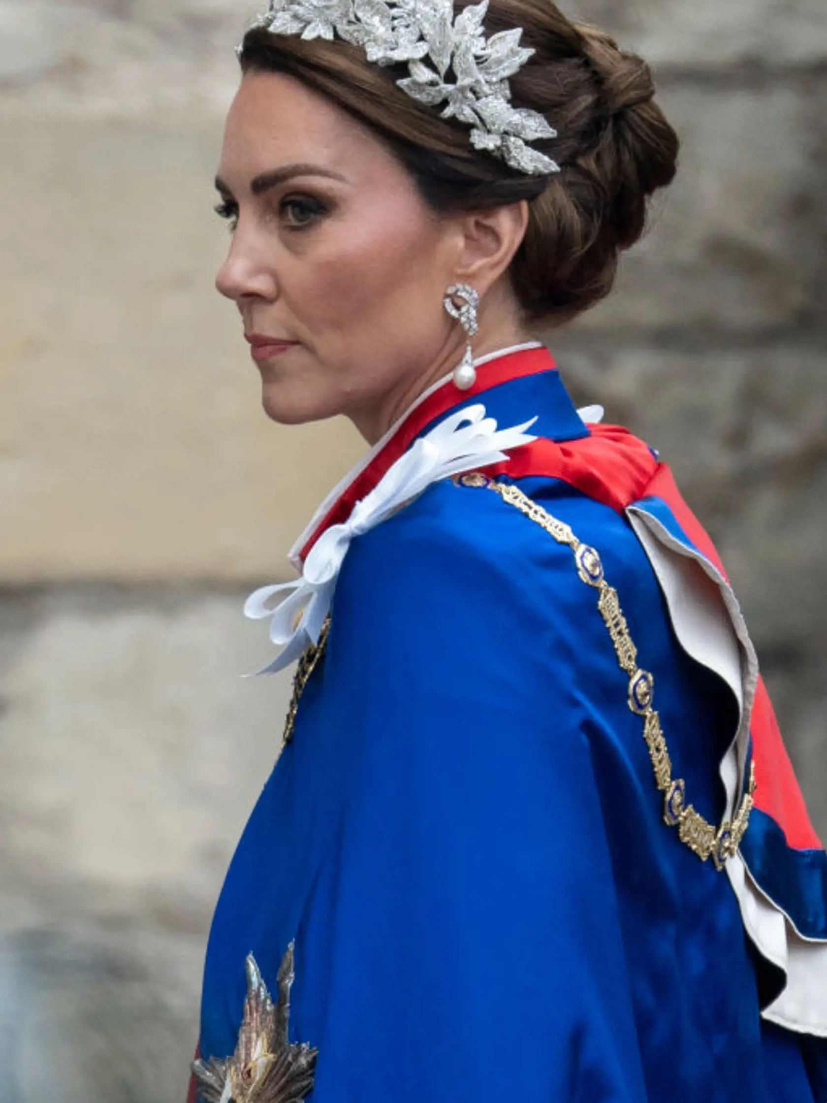 Princezná Kate mala na sebe tradičný ceremoniálny plášť. Pod ním slonovinové šaty od Alexandra McQueena a 3D čelenku, rovnako tak aj jej dcéra, princezná Charlotte.