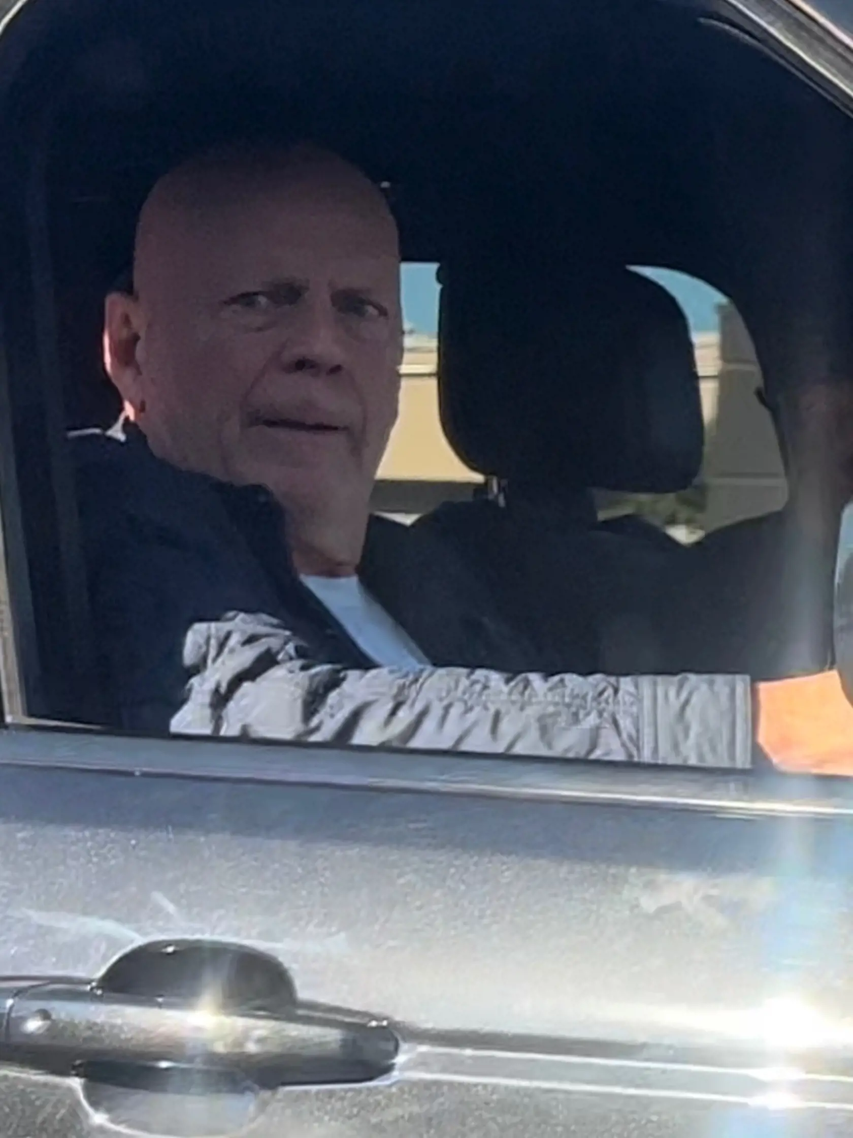 Herca Brucea Willisa odfotili 30. októbra 2023 sediac na sedadle spolujazdca v čiernom Range Roveri. Vozil ho bodyguard.
