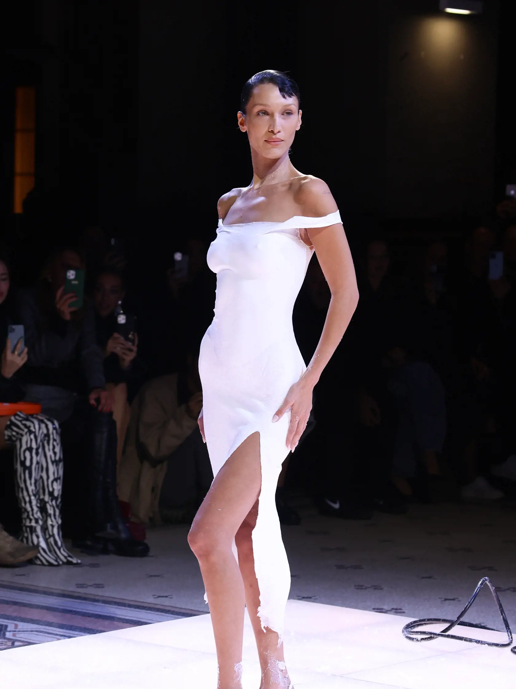 Na prehliadke francúzskej značky Coperni vystúpila v rámci Parížskeho týždňa módy aj takmer úplne holá Bella Hadid. Intímne partie jej zakrývali len skromné nohavičky a prsia si sama prekryla rukou. Ohromení hostia sledovali, čo sa asi bude diať, keďže šaty, ktoré mala kráska predviesť, neboli v dohľade. Keď však na jej  zvodné krivky začali aplikovať bielu farbu, všetci pochopili, čo sa deje - garderóba teraz nepochádza z krajčírskej dielne, ale "plechovky"!