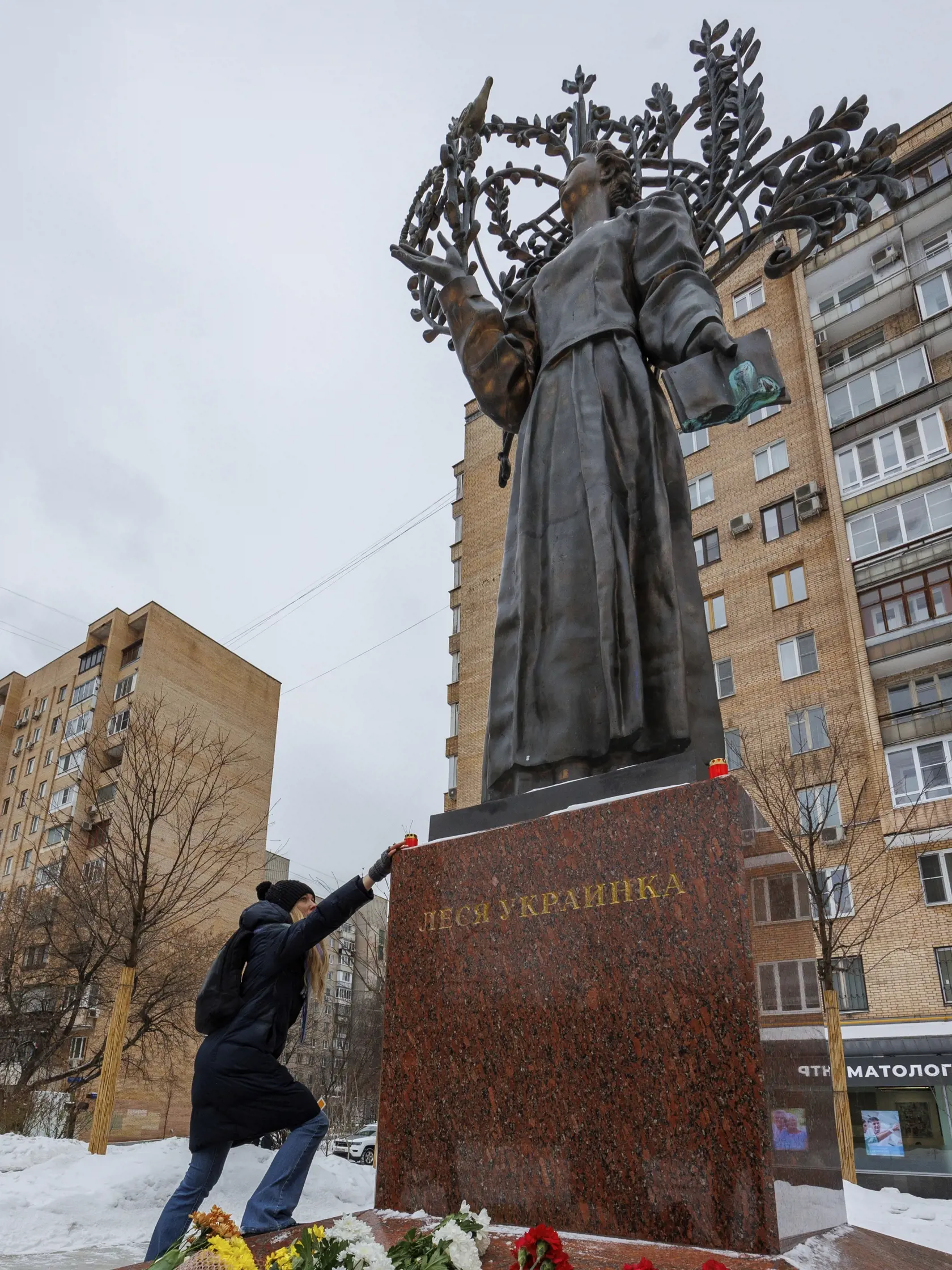 Žena kladie kvety na sochu ukrajinskej spisovateľky Lesie Ukrajinky počas prvého výročia ruskej agresie na Ukrajine 24. februára 2023 v Moskve.