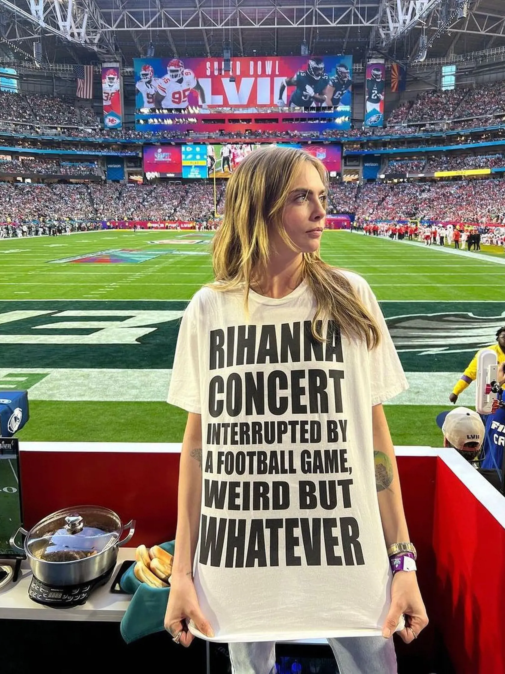 Cara Delevingne, ktorá si na tribúne dvihla tričko, ukázala sexi telo aj potlač s Rihanninou tvárou.