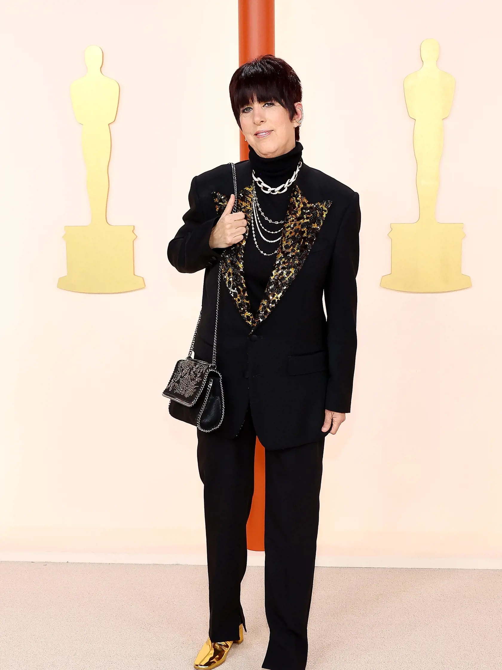 Skladateľka Diane Warren prišla v bizarnom vzhľade, ktorý obsahoval čierny oblek s leopardím vzorom a metalické zlaté topánky.