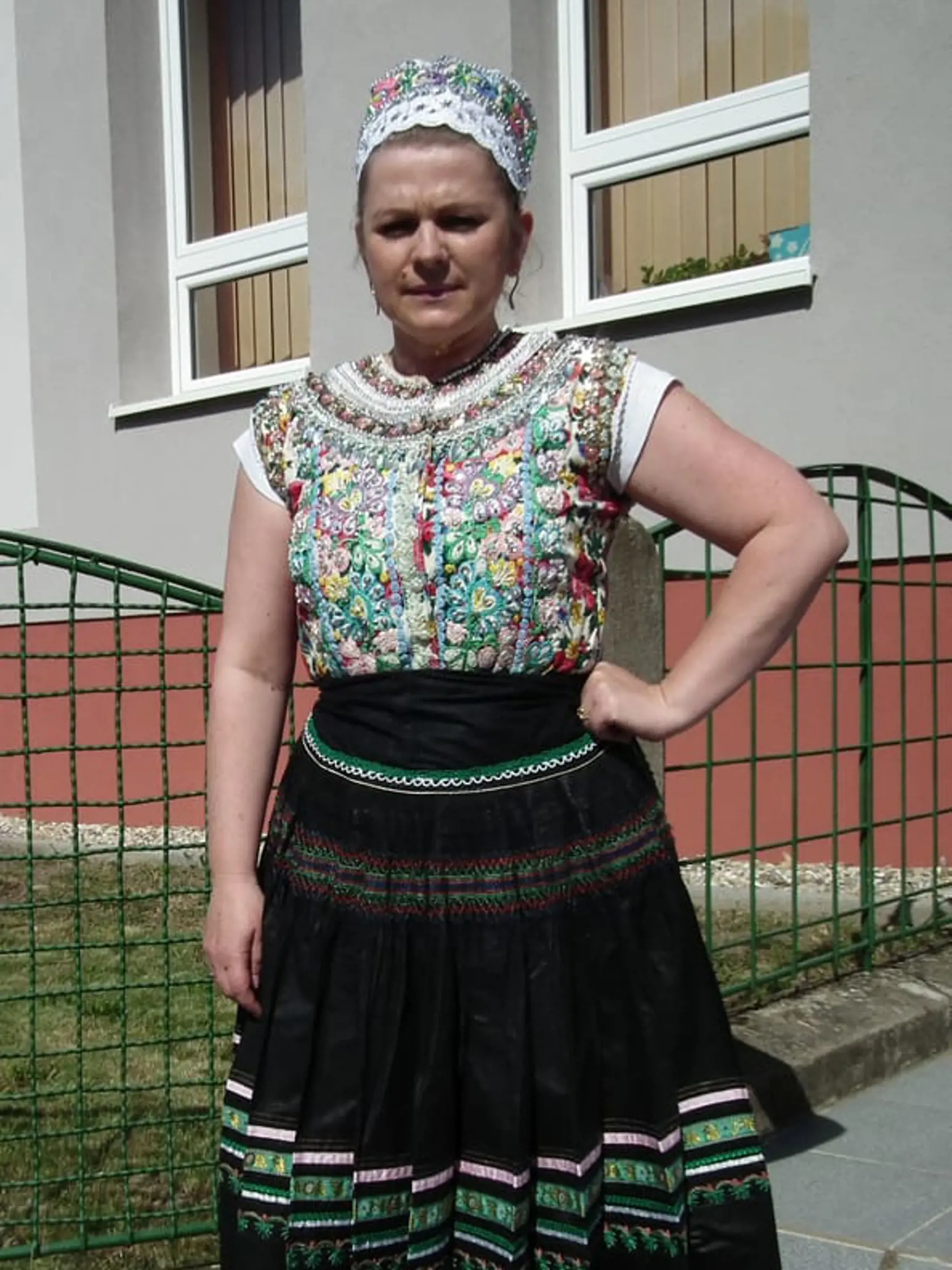 Adriana má na sebe oblečenú najstaršiu formu nádherne vyšívaného tekovského slávnostného kroja, pričom takáto zástera sa nosila okolo roku 1920. Na seba ho mávala vydatá mladá žena, ktorá musela k mať k nemu aj čepiec, a to buď takýto sviatočno-pracovný, alebo úplne sviatočný, ktorý bol s akýmisi rohami na boku. Dnešné ženy si rohaté čepce nasadia už len veľmi zriedka a nahradili ich jednoduchšími.