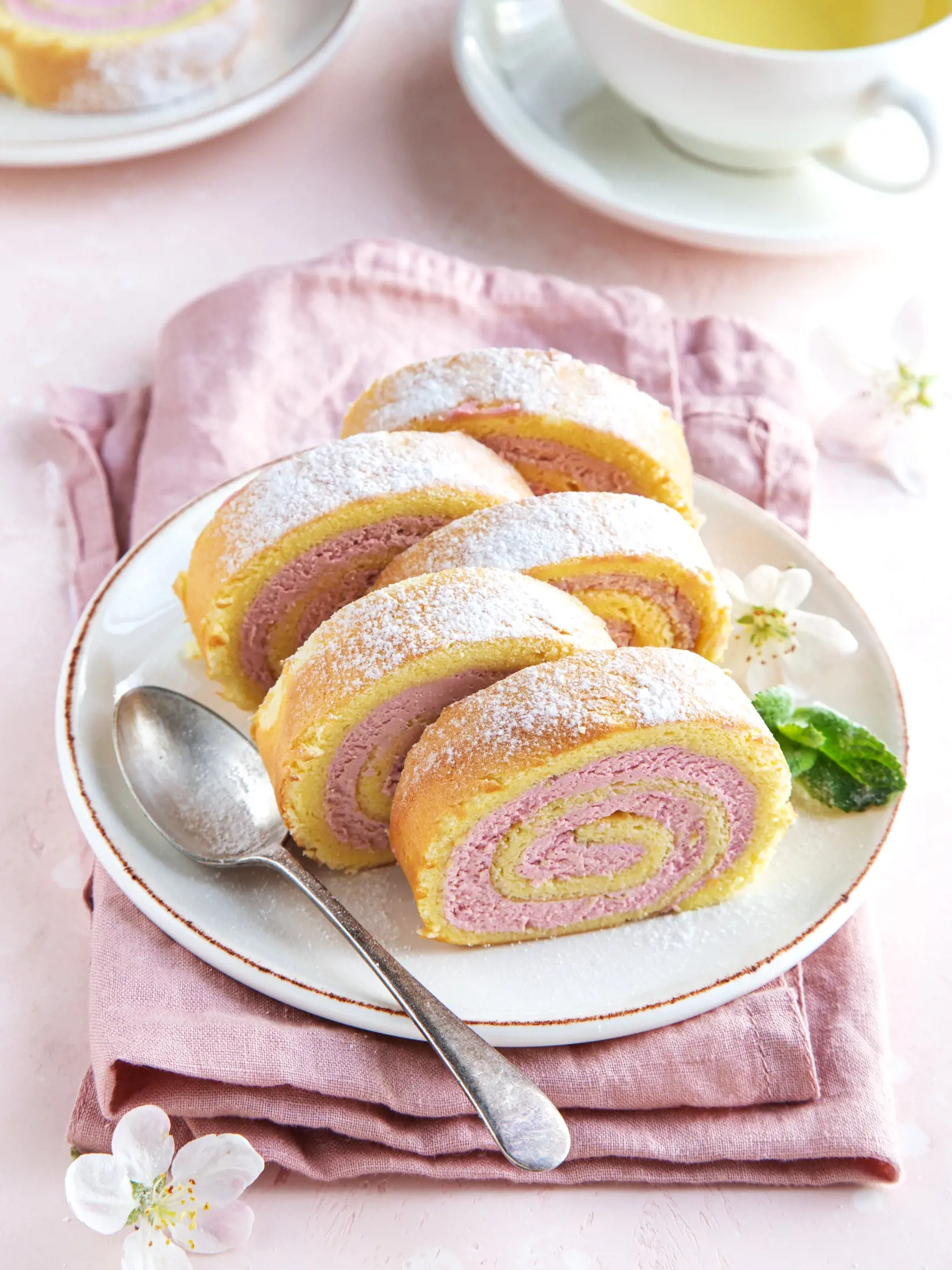 slised strawberry swiss roll  cake on white plate, wooden background, selective focus