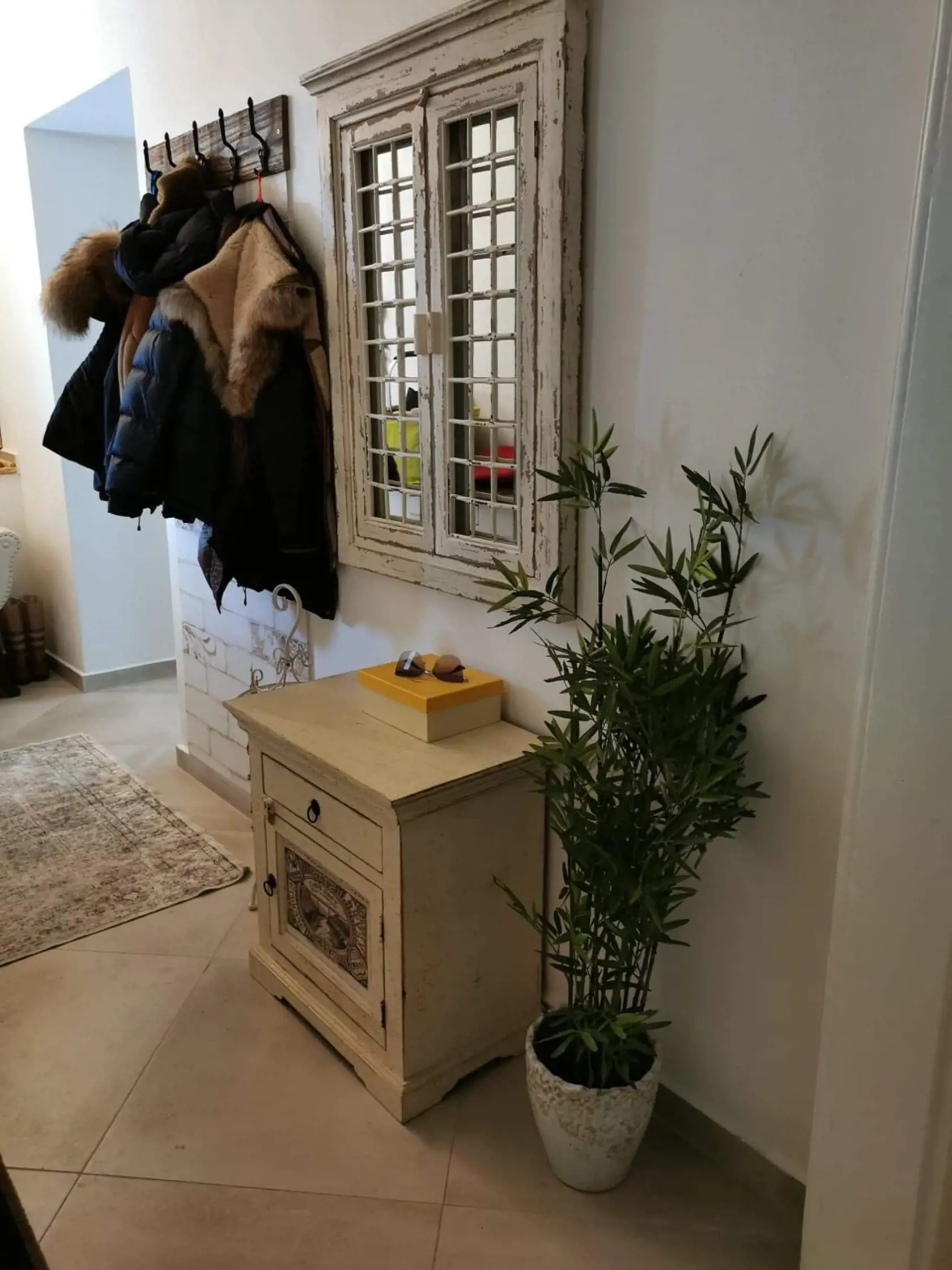 Jednoduchý vešiak na kabáty vedľa falošného okna slúžiaceho iba ako dekorácia.