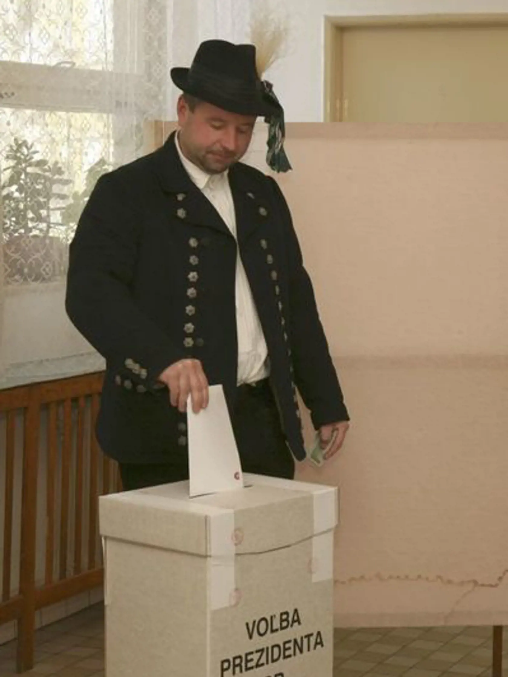 Druhé kolo prezidentských volieb 2014: Muž v kroji hádže hlasovací lístok do urny vo volebnej miestnosti v Martovciach, okres Komárno.