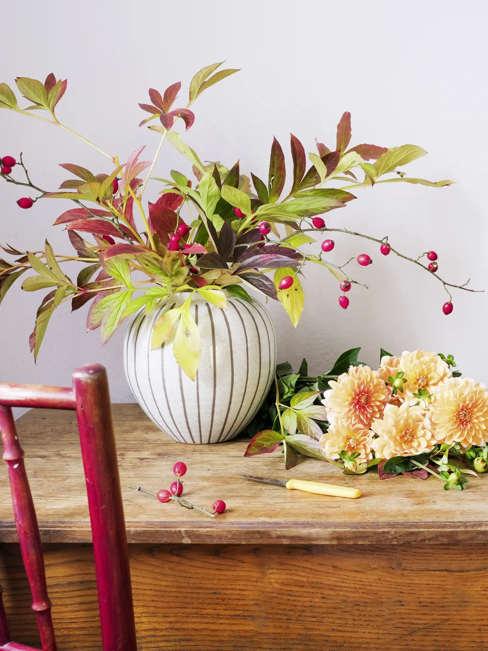 An autumn bouquet in a vase and flowers on the florist's table during the creation of a flower arrangement