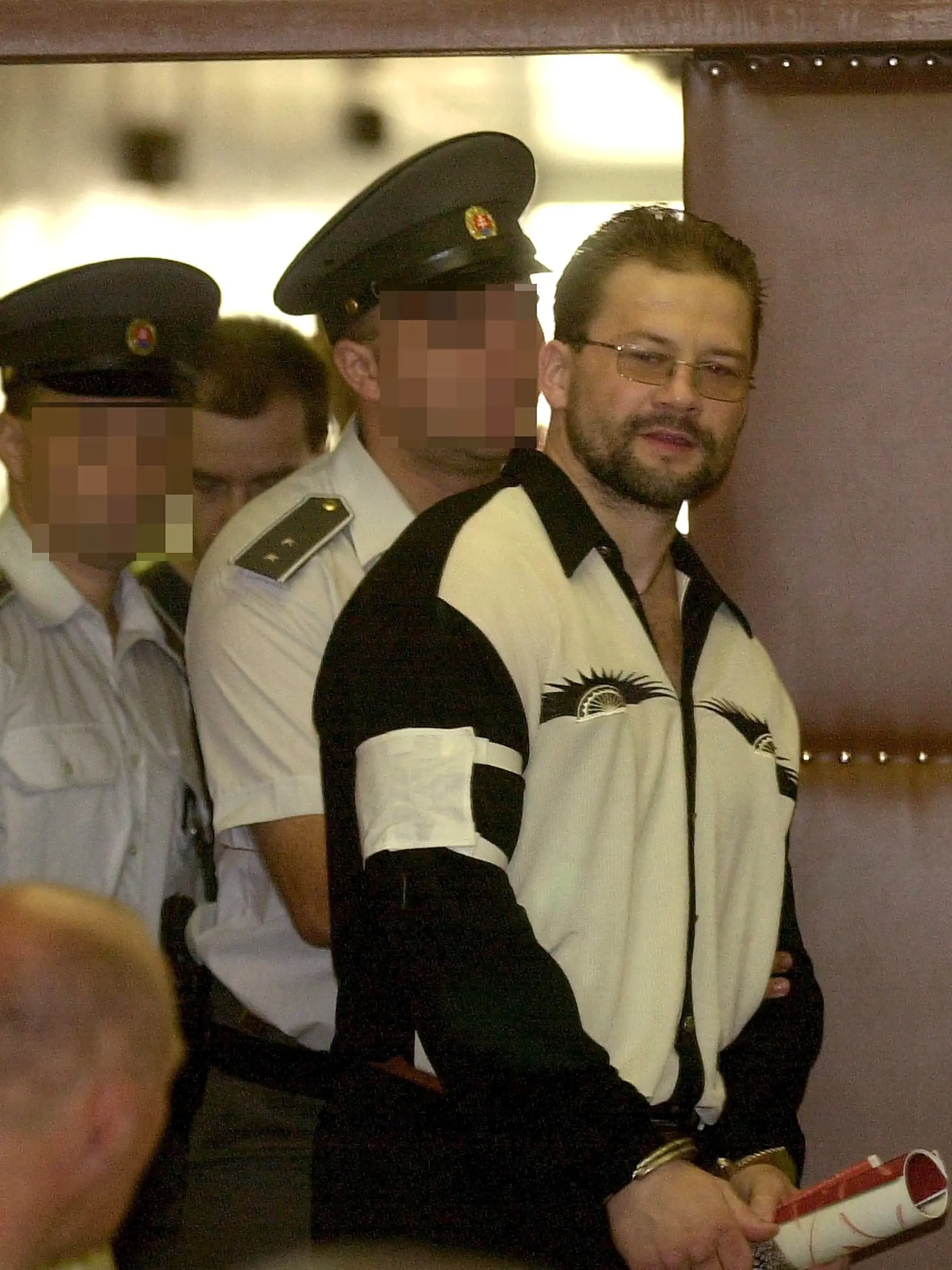 Policajti privádzajú Boržu do pojednávacej siene.