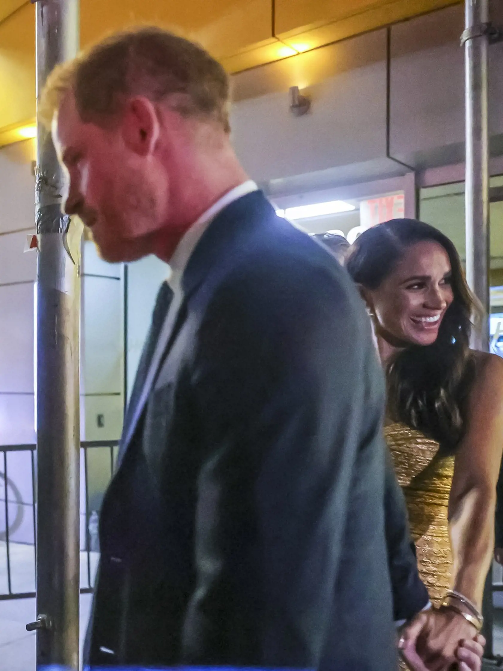 Meghan si na prestížnu udalosť obliekla zlaté obtiahnuté šaty s hlbokým výstrihom za 1 700 eur z dielne Johanny Ortiz, ktoré zladila s malou čierno-zlatou kabelkou značky Carolina Herrera za 1 100 a s topánkami na vysokých opätkoch z dielne Toma Forda za 1 350. Aby toho nebolo málo, cenu outfitu zvýšila zlatým náramkom Cartier Love v hodnote 7 350 eur.
