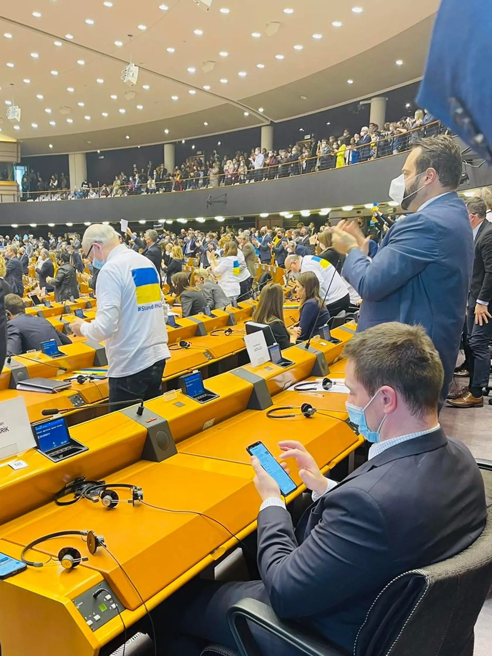 Europoslankyňa Lucia Ďuriš Nicholsonová uverejnila na facebooku fotografie z europarlamentu. Potom, ako sa poslancom prihovoril Volodymyr Zelenskyj, europoslanci tlieskali v stoji. Uhrík zostal sedieť a hral sa na mobile.