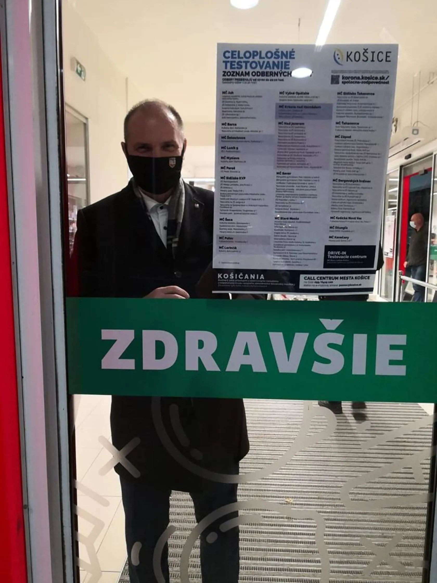 Primátor vylepuje zoznamy odberových miest v predajni potravín.
