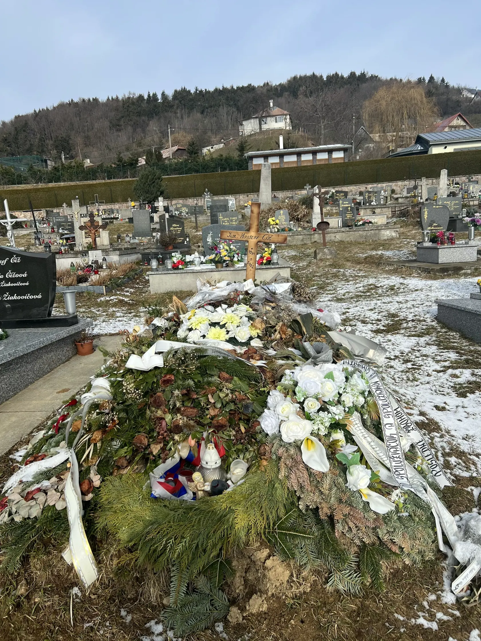 Namiesto pomníka tu dočasne stojí len jednoduchý drevený kríž a hrob pôsobí ako keby sa oň nik nestaral - ležia na ňom staré kvety ešte od pohrebu.